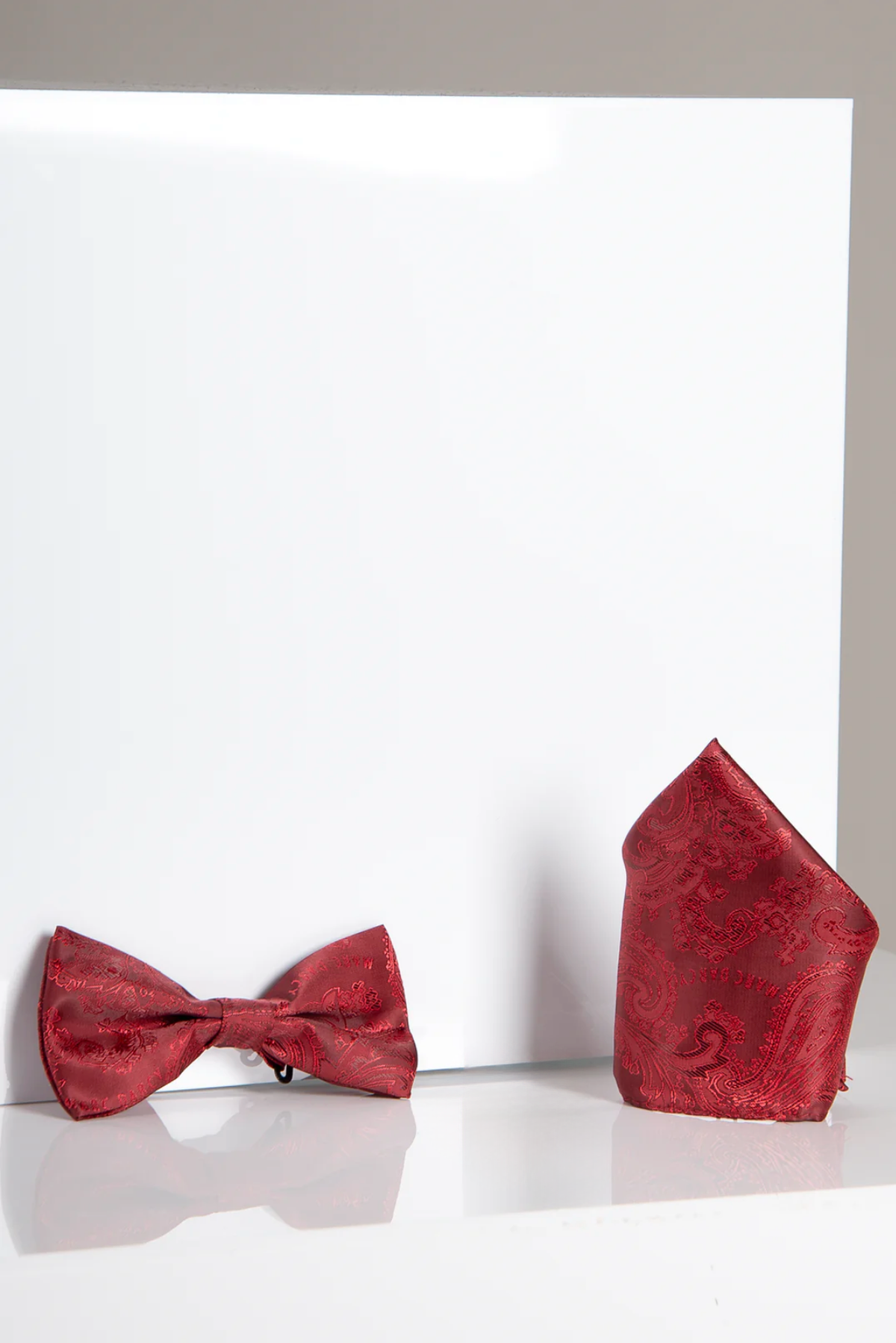 The Accessory MD PAISLEY Wine Paisley Bow Tie and Pocket Square Set is shown on a white surface—an ideal choice for enhancing your evening attire.