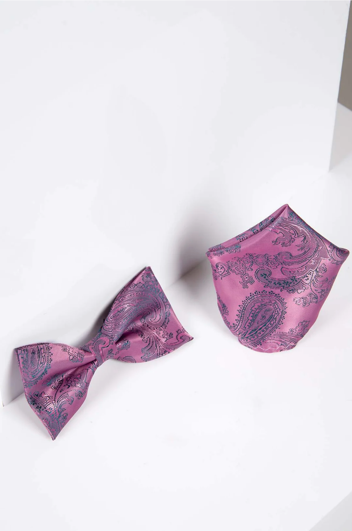 The Accessory PAISLEY Pink Paisley Bow Tie and Pocket Square Set is displayed on a white surface with a plain white background, perfect for enhancing any evening outfit.