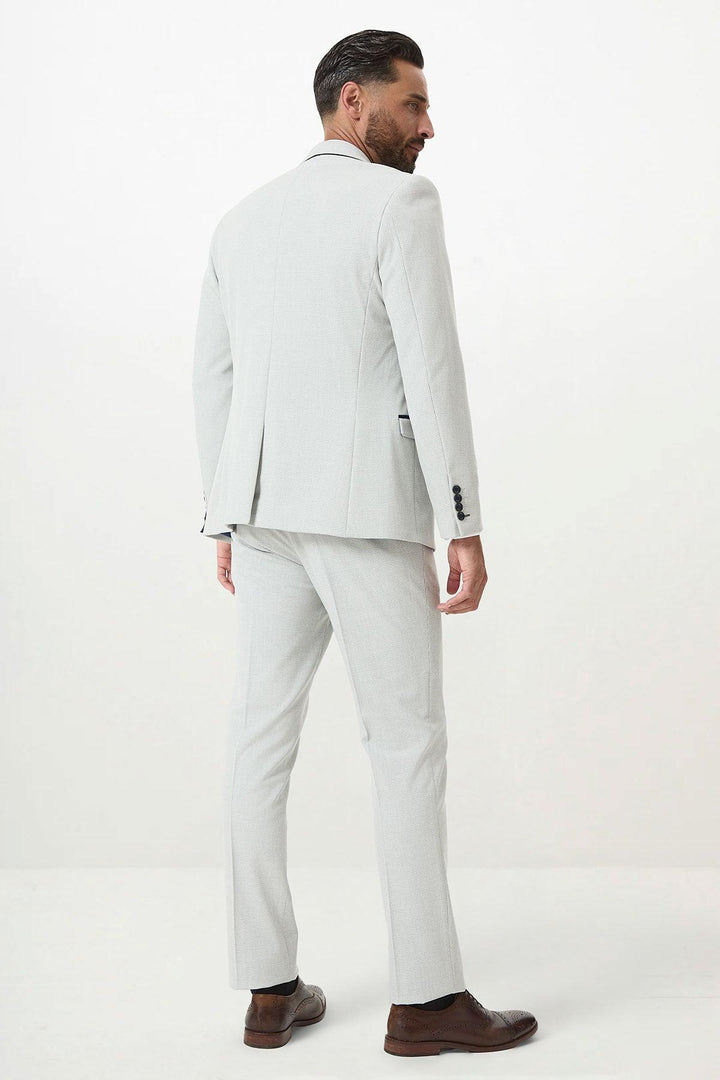 A man with dark hair and a beard models the Marc Darcy BROMLEY - Stone Check Suit with Kelvin Navy Waistcoat, styled in a slim fit with brown dress shoes, standing with his back to the camera against a plain white background.