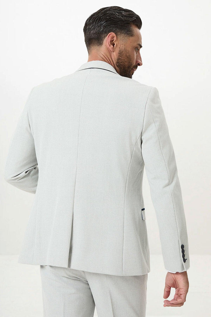 A man with dark hair and a beard is seen from behind wearing the Marc Darcy BROMLEY Stone Check Suit with Kelvin Navy Waistcoat, his refined style accented by a minimal, light background.