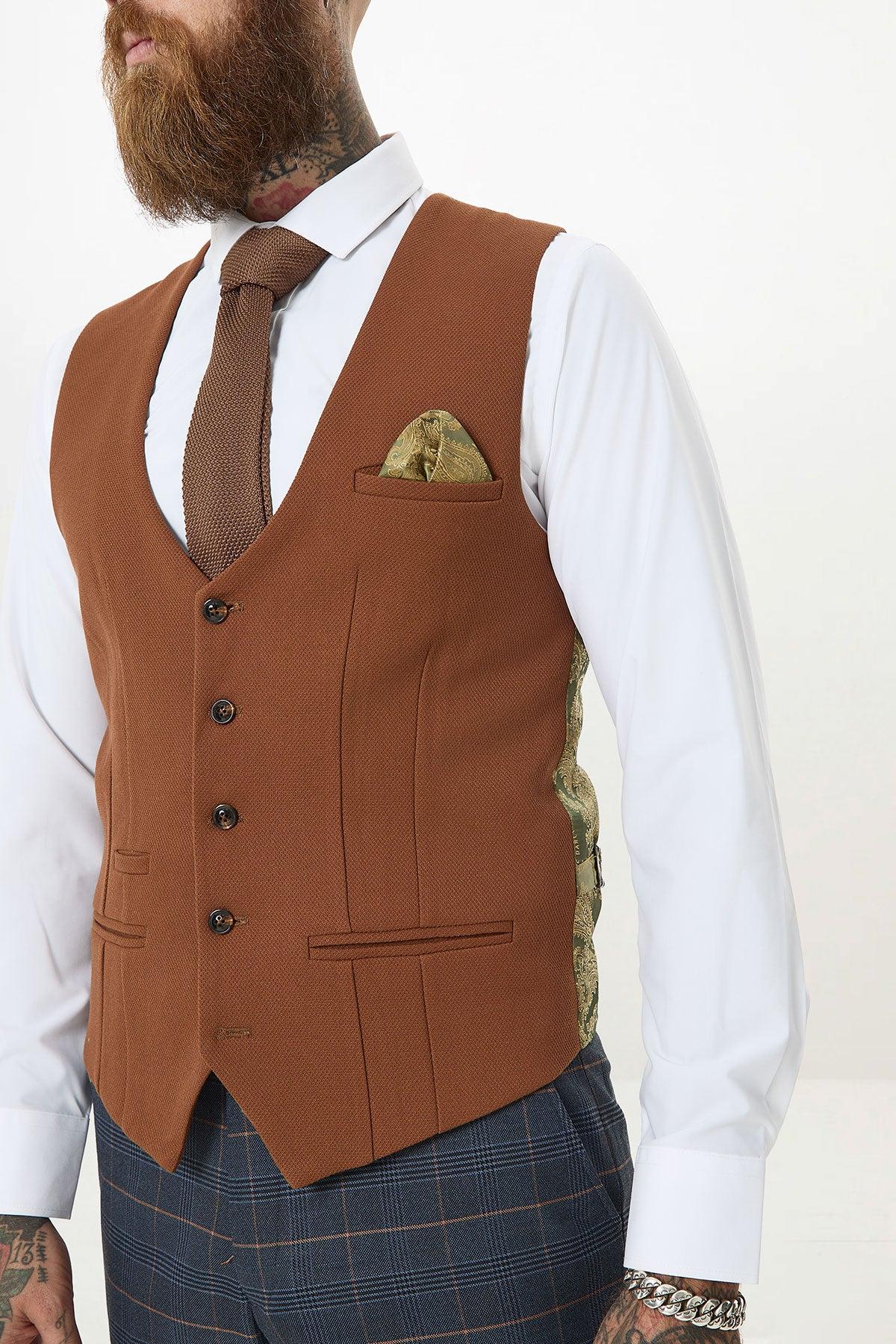 A bearded, tattooed man wears the marcdarcy JENSON Marine Navy Check Suit with a Kelvin Tan Waistcoat, pairing it with a white shirt and brown knit tie.