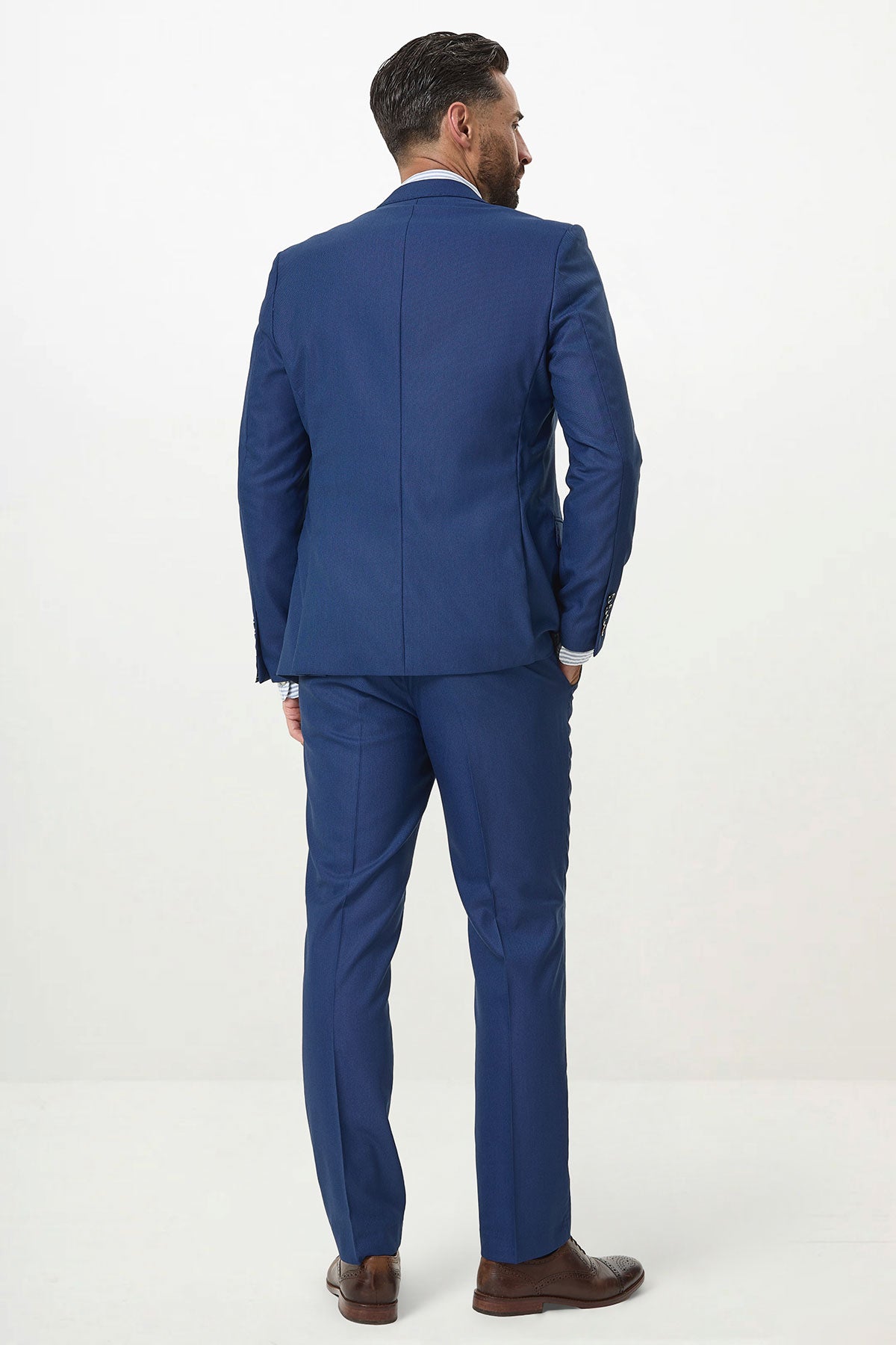 A man models the Marc Darcy DANNY Royal Blue Three Piece Suit with single breasted waistcoat and brown shoes, standing with his back to the camera against a white background, highlighting modern workwear style.