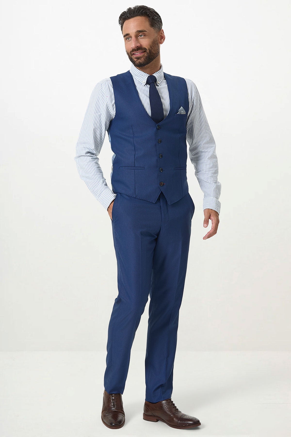 A man with a beard wears the Marc Darcy DANNY Royal Blue Three Piece Suit with a single breasted waistcoat, paired with a striped shirt, blue tie, and brown shoes. He's smiling and posed against a plain white background—perfect for workwear.