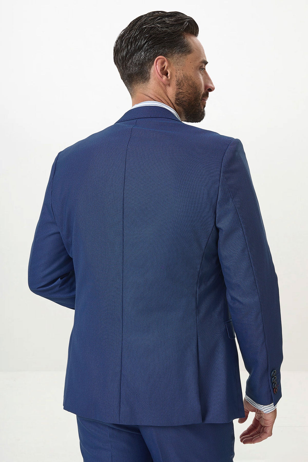 A man with short dark hair, beard, and mustache is seen from behind wearing the Marc Darcy DANNY Royal Blue Tailored Blazer and matching pants, creating a modern workwear look against a plain white background.