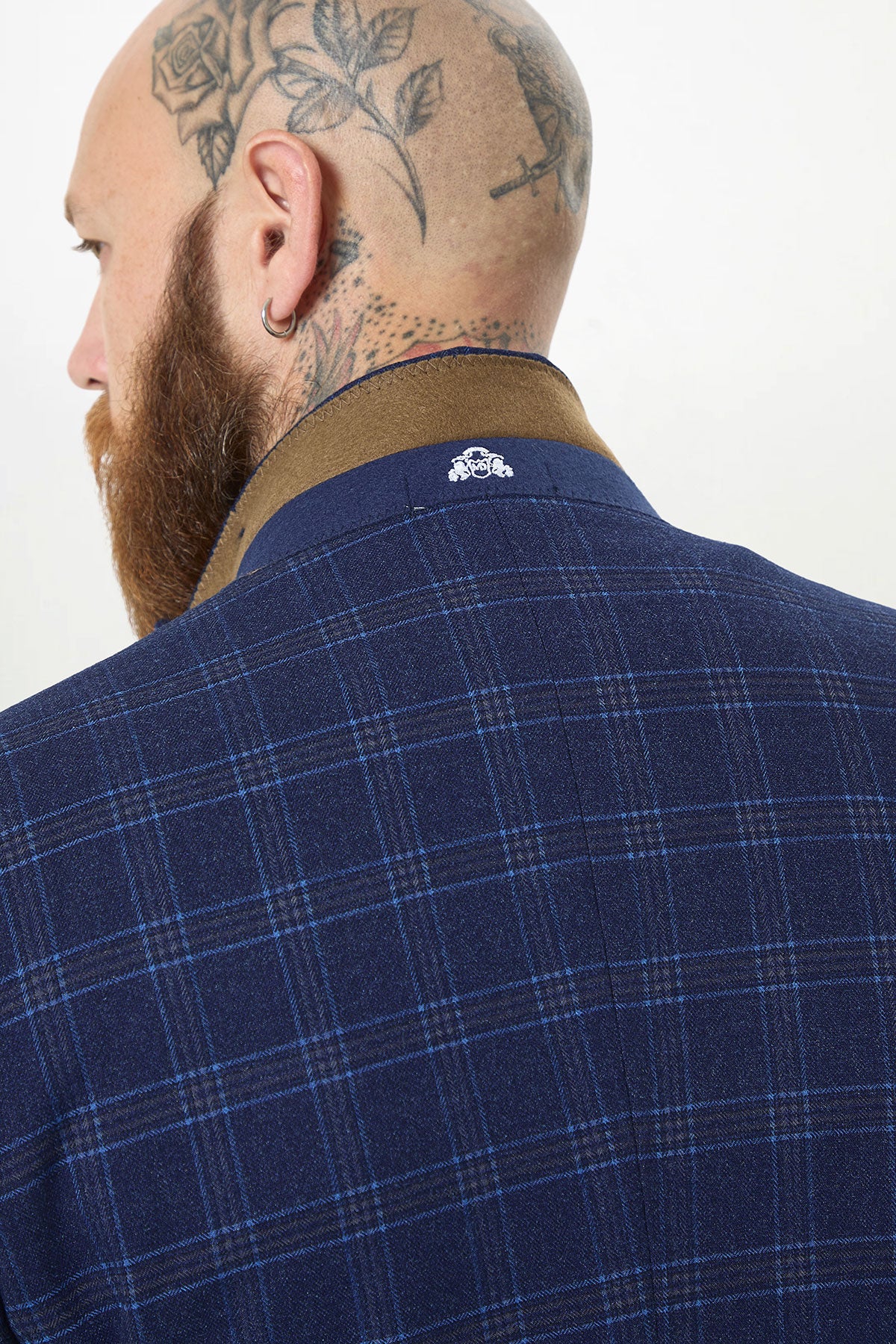 A man with a tattooed bald head and beard is seen from behind wearing the marcdarcy CHIGWELL Blue Tweed Check Blazer, featuring a brown collar and a small white emblem on the back.