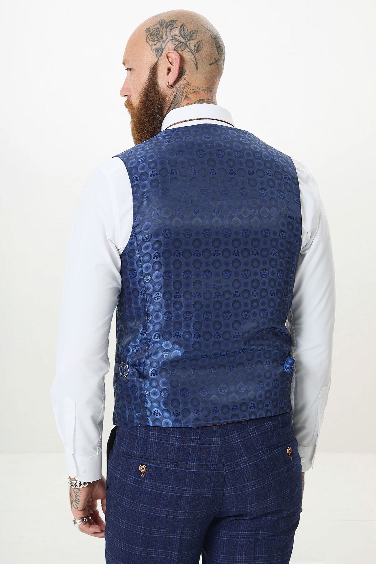 Back view of a man in the marcdarcy CHIGWELL Blue Tweed Check Three Piece Suit—styled with a white shirt and tattoos on his head and beard. A bold wedding guest look.