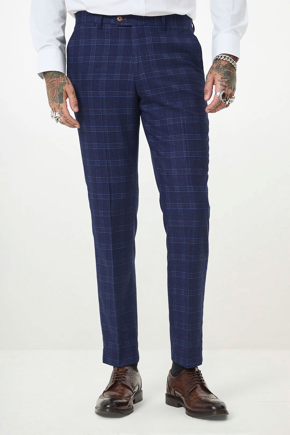 A person wearing the marcdarcy CHIGWELL blue tweed check three piece suit with a crisp white shirt and brown wingtip shoes. Their hands display tattoos and rings.