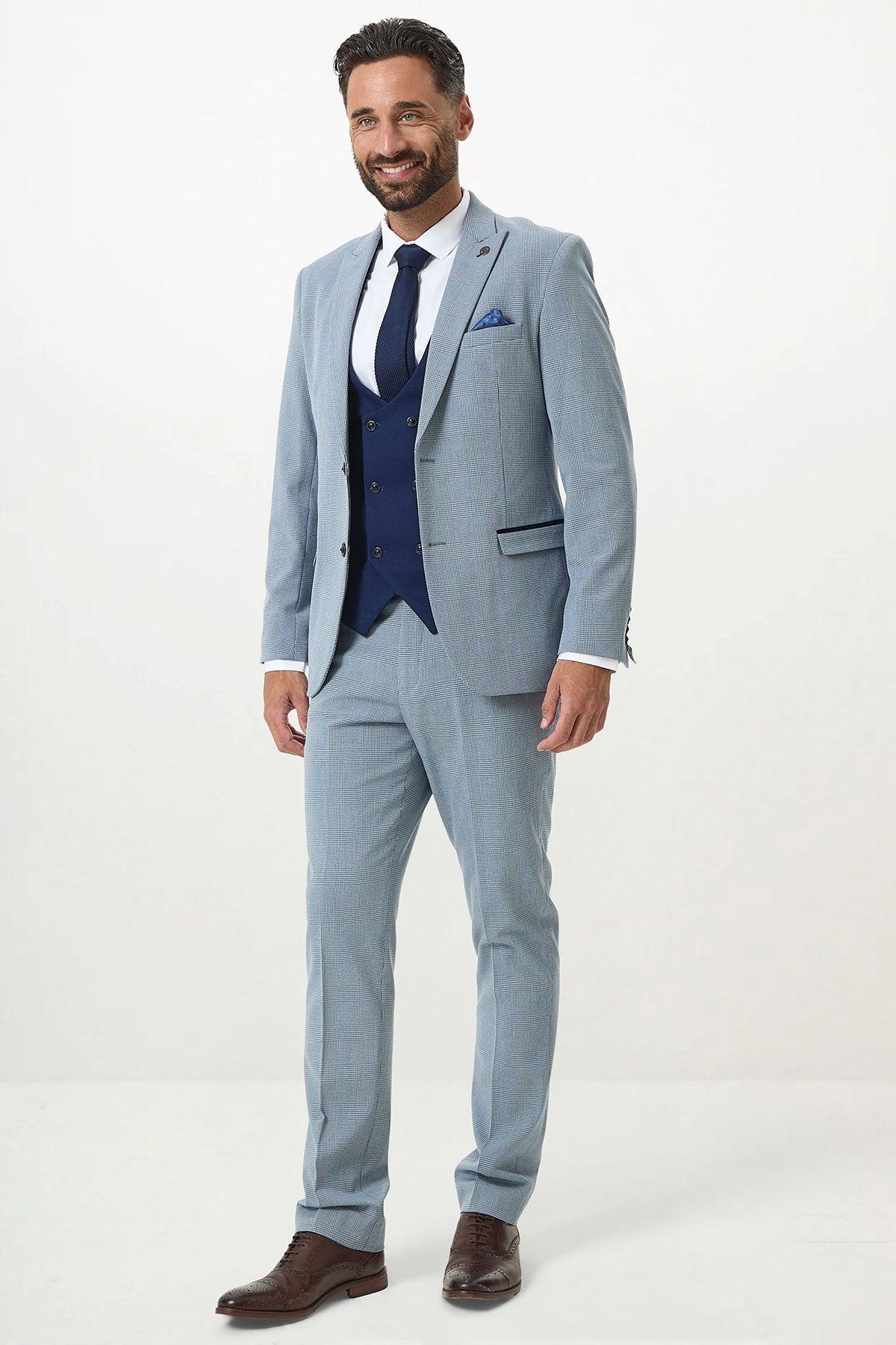 Man in a Marc Darcy BROMLEY Sky Check Suit with Kelvin Royal Waistcoat, navy tie, and brown shoes.