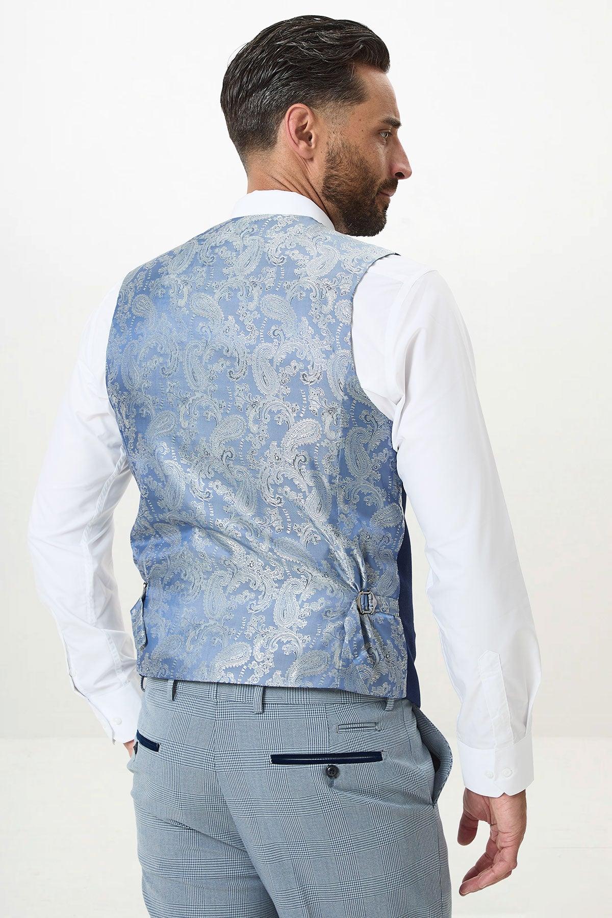 A man with dark hair and beard is seen from the back wearing the Marc Darcy BROMLEY Sky Check Suit with Kelvin Royal Waistcoat—an elegant wedding choice. The waistcoat features a light blue check pattern and an adjustable strap; background is plain white.