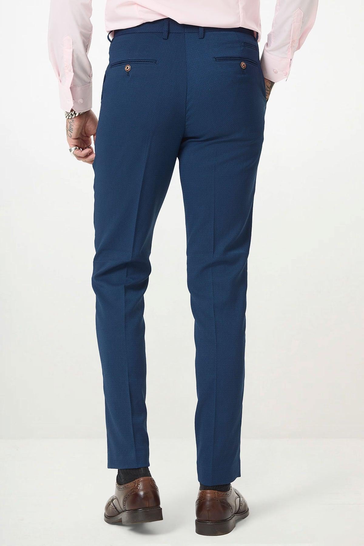 A person in marcdarcy’s MAX Royal Blue Trousers with contrast buttons, a light pink shirt, and brown dress shoes stands with their back to the camera, hands at their sides, exemplifying classic formal slim-fit office wear.