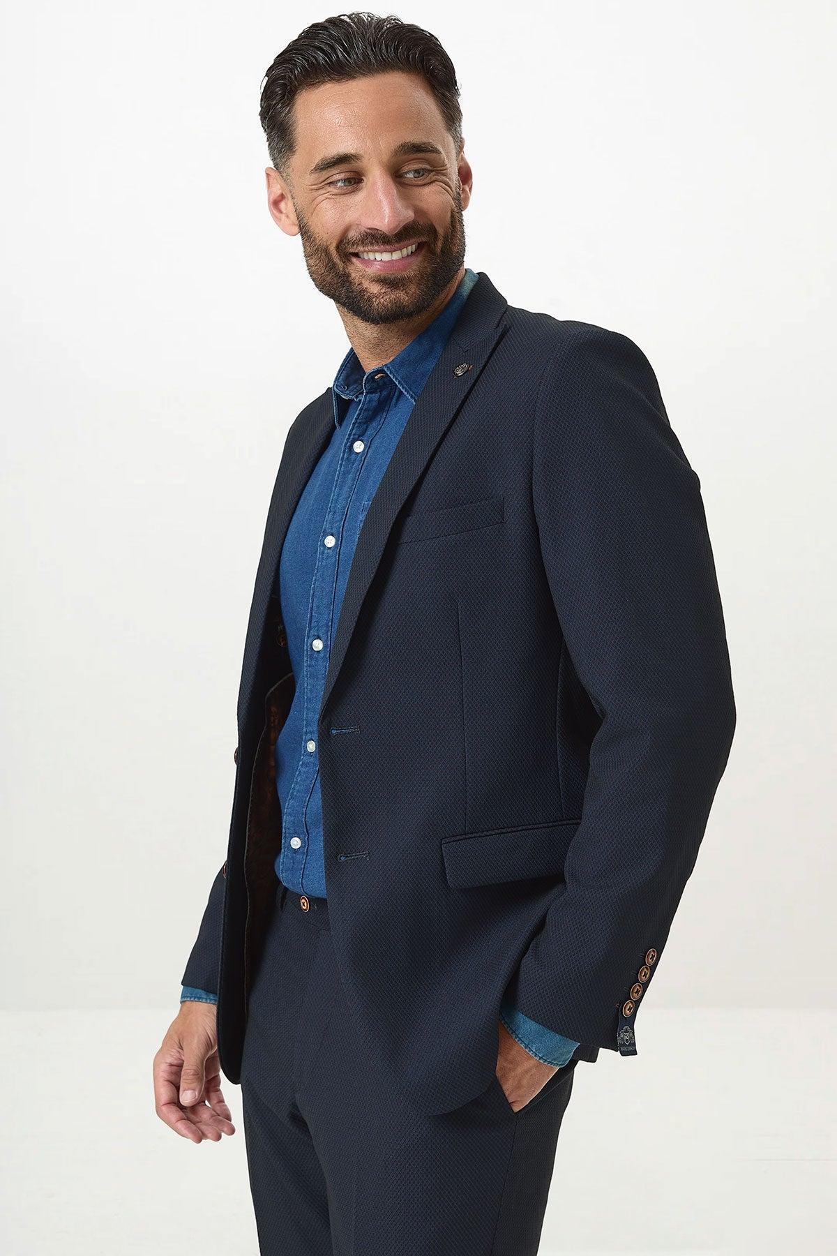 A man with dark hair and a beard smiles, wearing the marcdarcy MAX Navy Blue Blazer with Contrast Buttons over a blue shirt, standing against a light background—ideal for office wear.