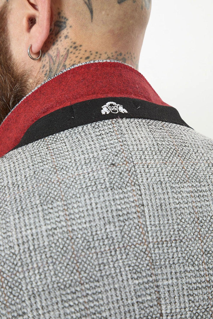 Close-up of a persons neck and shoulder wearing the marcdarcy KRIS Silver Grey Tweed Two Piece Suit in slim fit, with a red and black collar, small white embroidered logo, silver hoop earring, and tattooed neck.