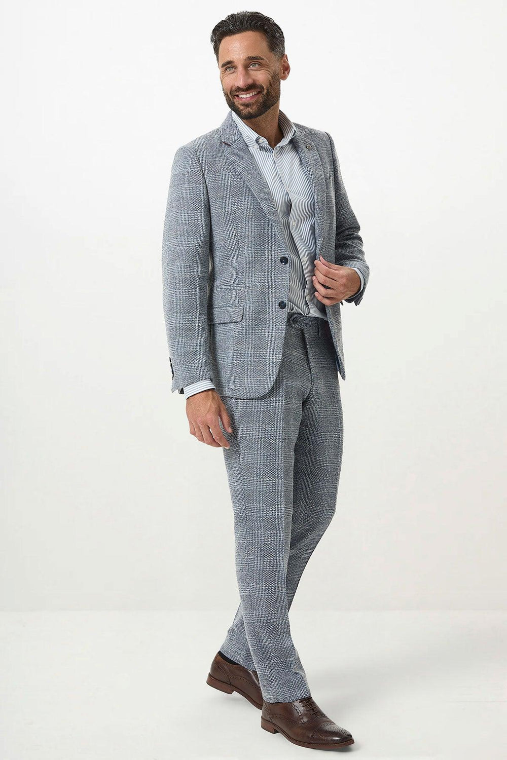 A man with short dark hair and a beard smiles while wearing the marcdarcy KRIS Sky Blue Tweed Two Piece Suit, standing against a plain white background.
