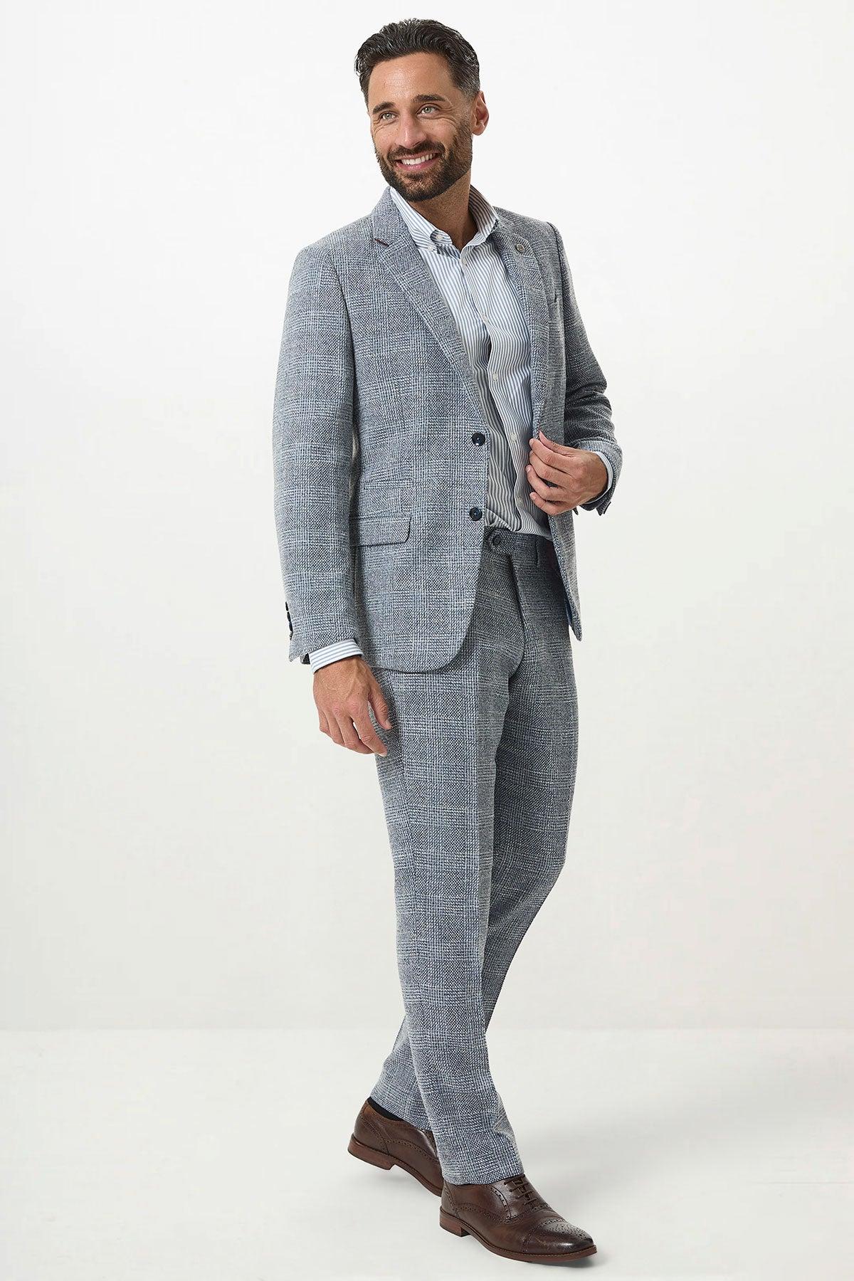 A man with short dark hair and a beard smiles while wearing the marcdarcy KRIS Sky Blue Tweed Two Piece Suit, standing against a plain white background.