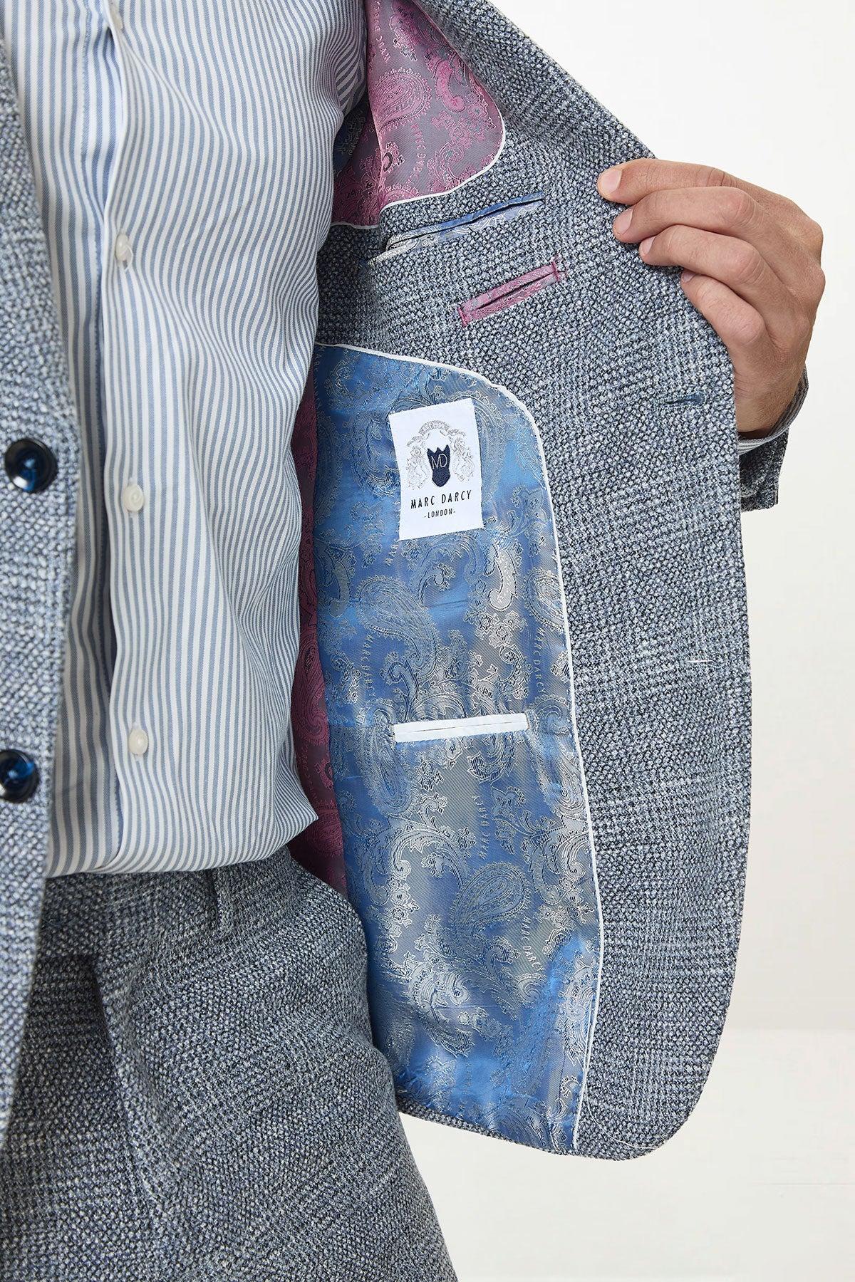 A man wears the marcdarcy KRIS Sky Blue Tweed Two Piece Suit with a striped shirt. The jacket's lining has a blue paisley pattern and pink paisley on the lapel, plus a marcdarcy label inside this sharp suit.