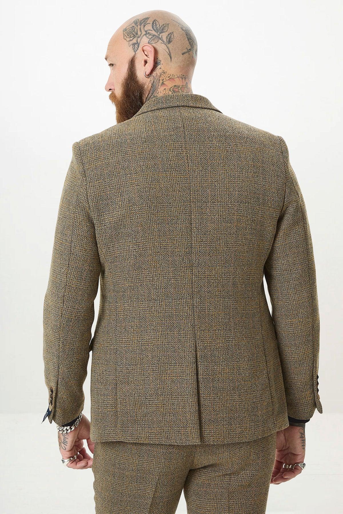 Back view of a tattooed man with a beard and hoop earring, showcasing modern style in the marcdarcy KRIS Tan Tweed Two Piece Suit featuring classic Prince of Wales check.