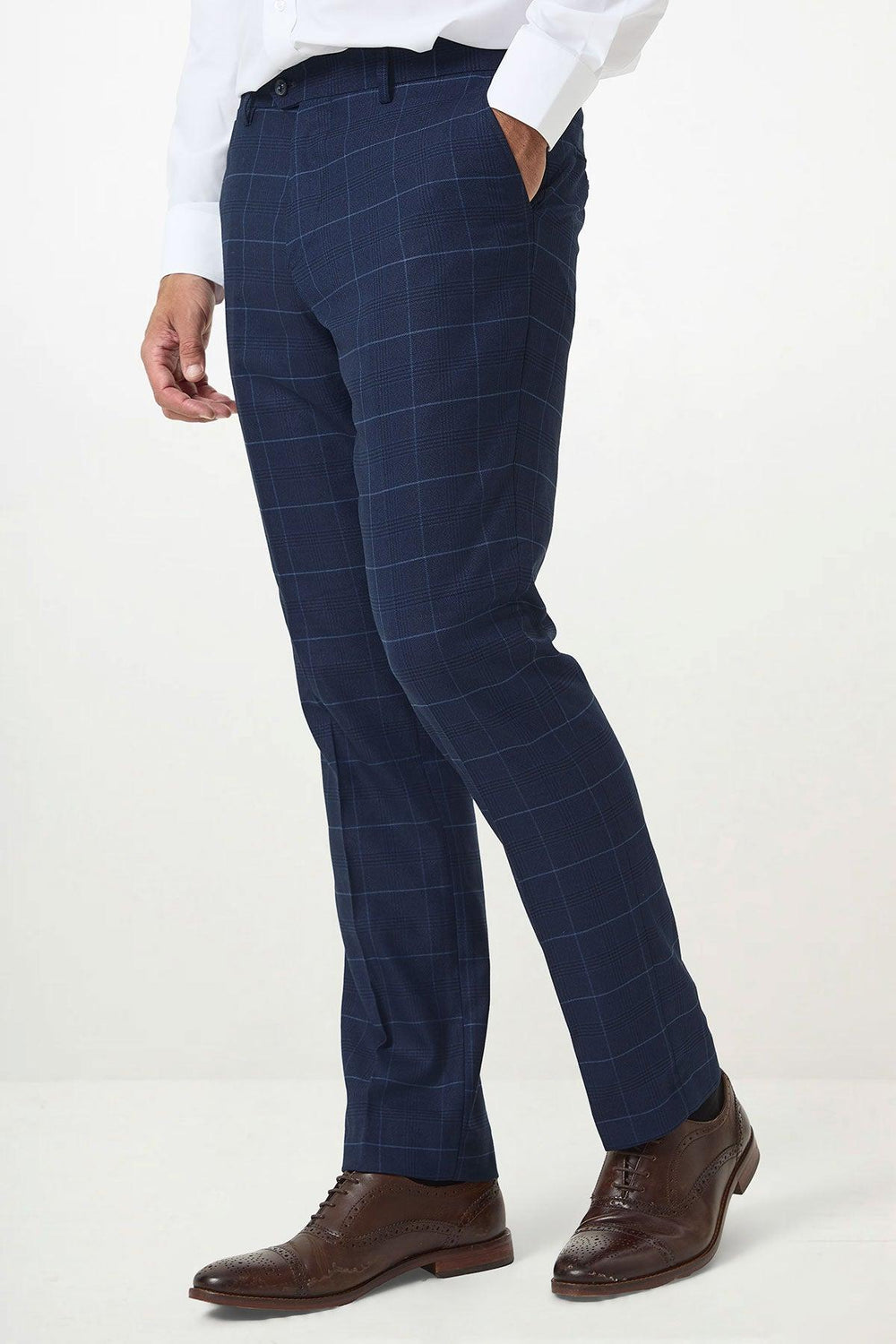 A person stands against a plain light background, wearing Marc Darcy EDINSON - Navy Sky Check Trousers, a white dress shirt, and brown leather dress shoes.