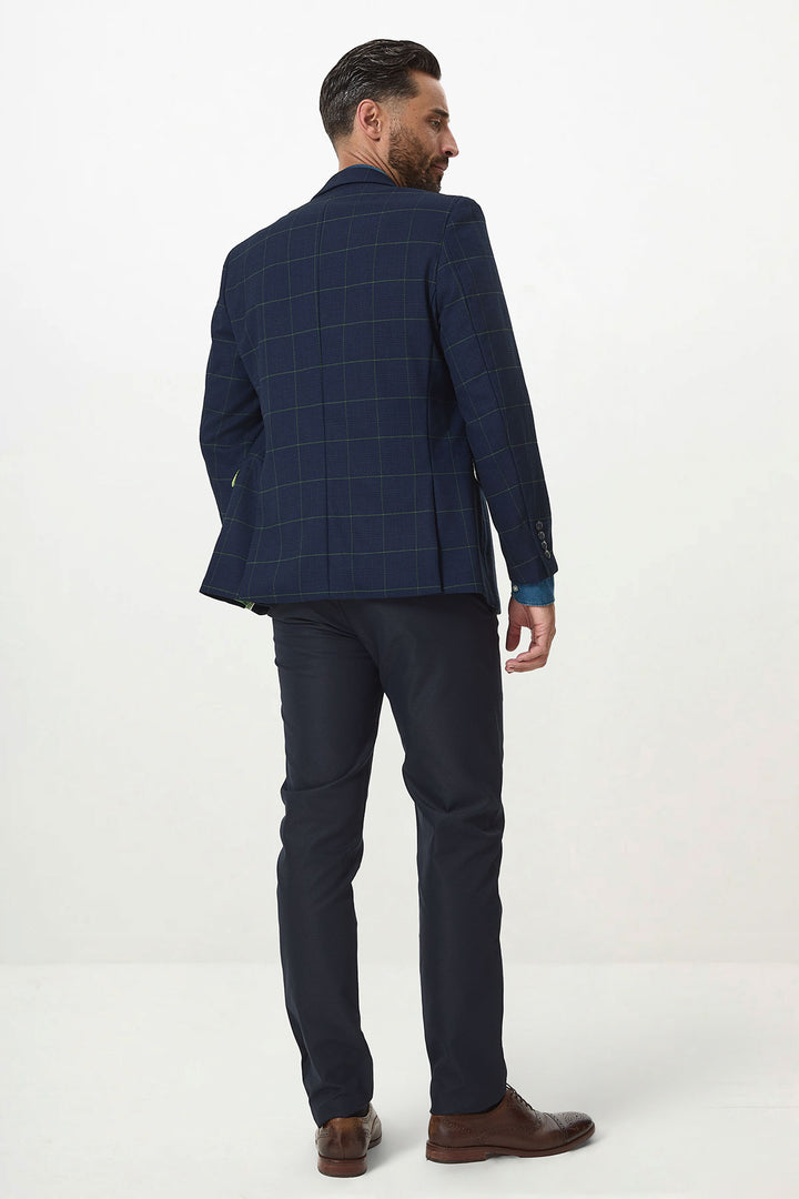 A man with dark hair and a beard, wearing the Marc Darcy EDINSON Navy Green Check Blazer with matching trousers and brown shoes, stands facing away and slightly to the side against a plain white background.