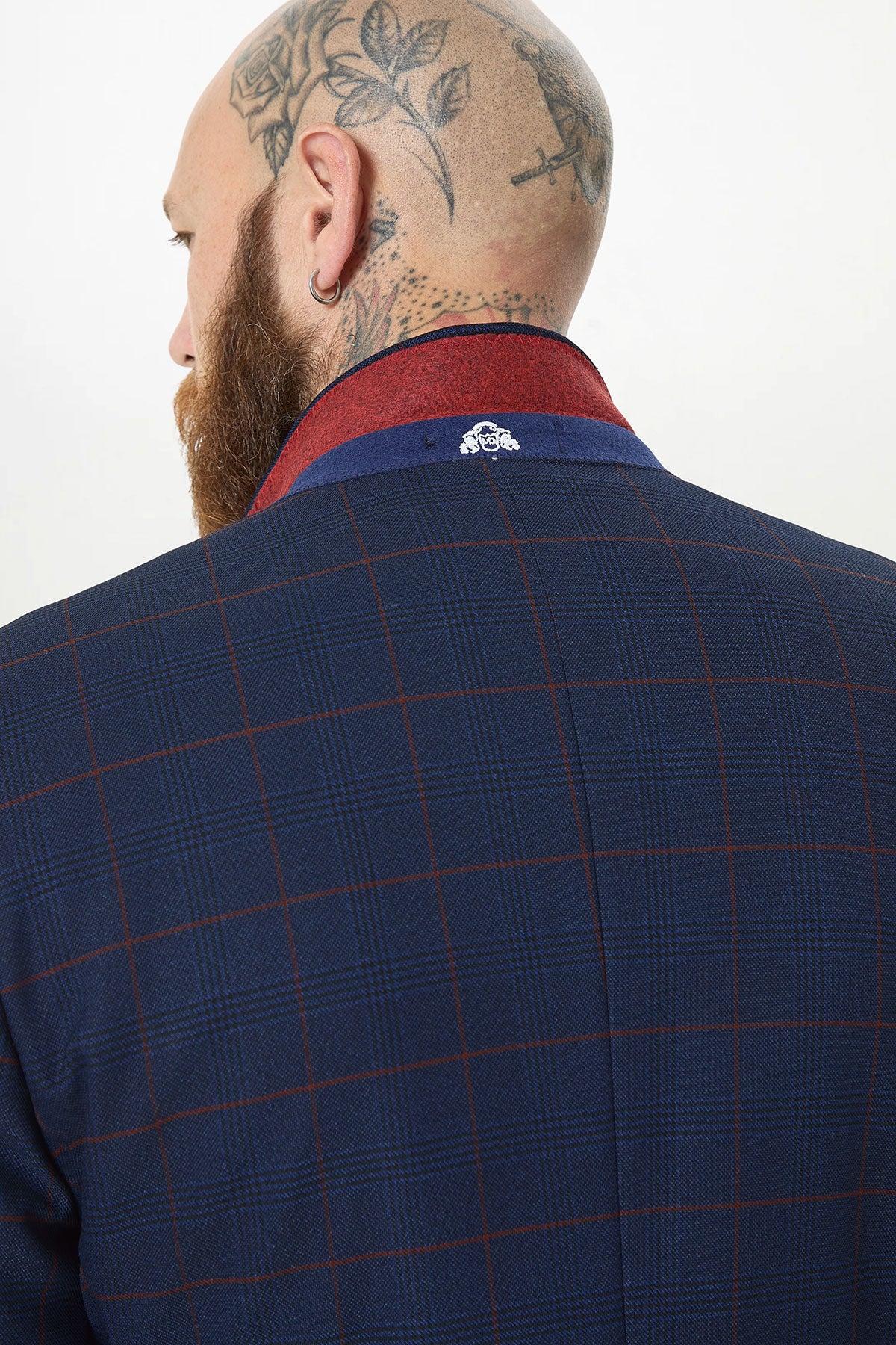 Close-up of a man in the Marc Darcy EDINSON Navy Wine Check Three Piece Suit, featuring a checkered jacket and slim tailored fit for a sharp, modern look. He has head tattoos and a beard.