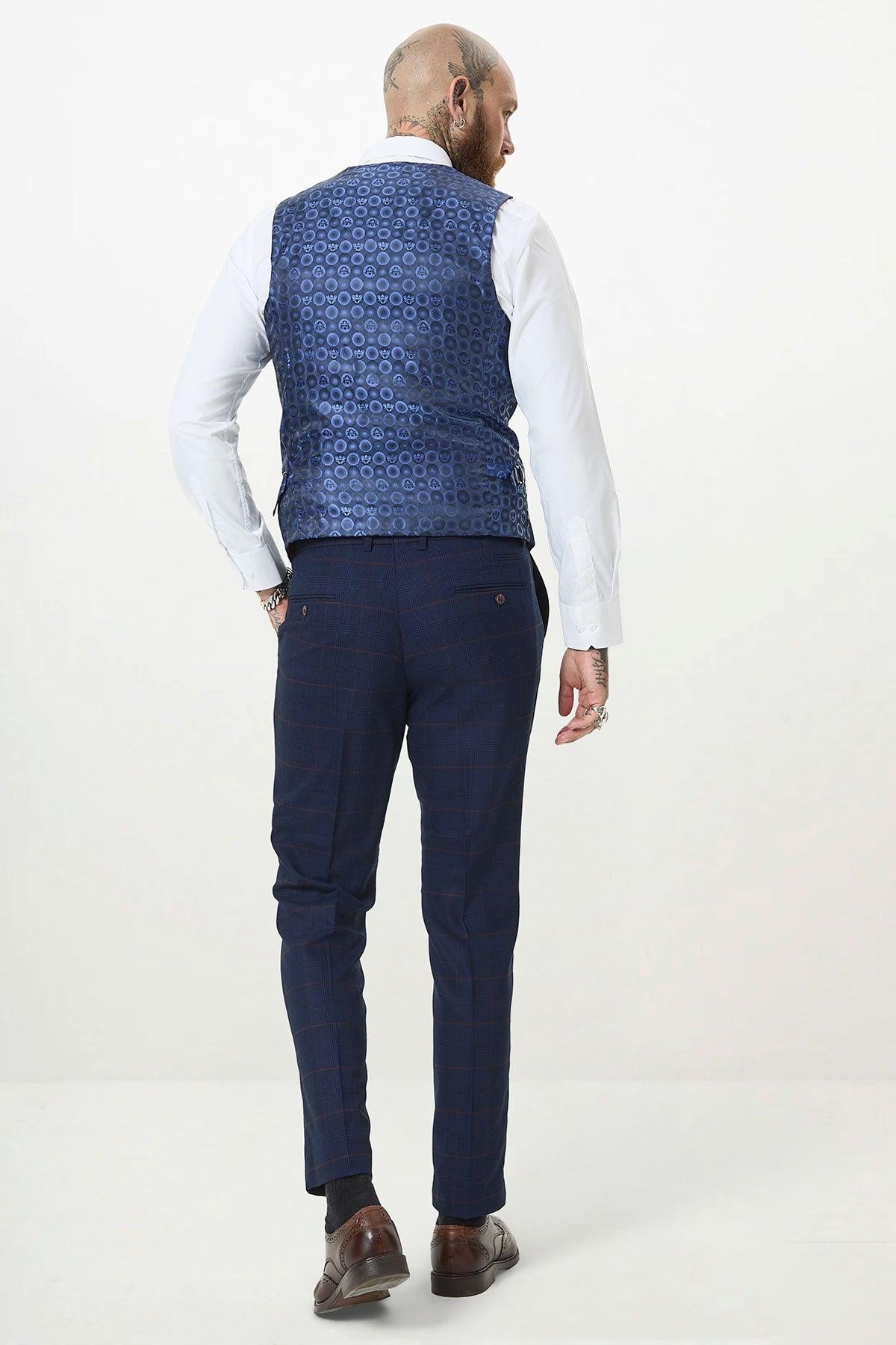 A man with tattoos stands facing away from the camera, wearing the Marc Darcy EDINSON Navy Wine Check Three Piece Suit against a plain light background.