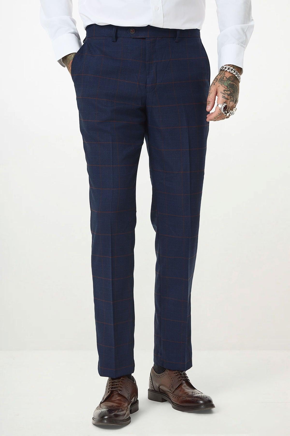 A person wears the Marc Darcy EDINSON Navy Wine Check Three Piece Suit with a crisp white shirt. Slim tailored pants, brown dress shoes, and hand tattoos are visible against a plain light background.