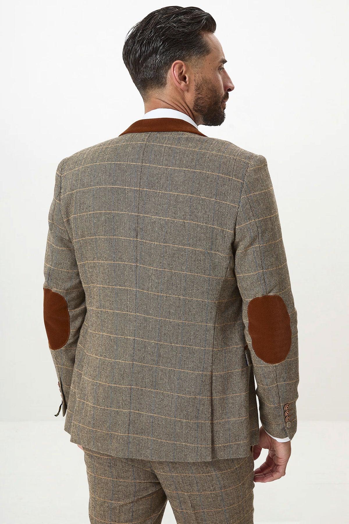 A man is seen from behind in the marcdarcy DX7 - Tan Tweed Check Three Piece Suit with double breasted waistcoat, featuring brown suede elbow patches and a velvet contrast collar. His dark hair contrasts with the plain white background.