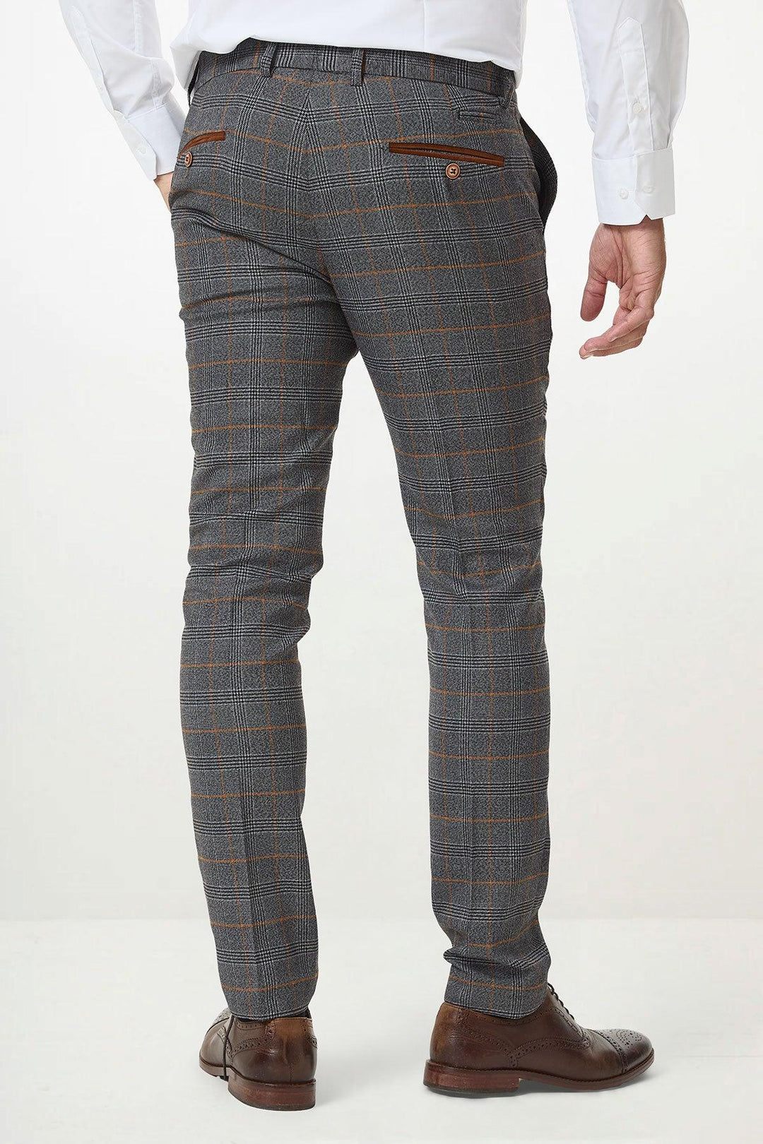 A man stands with his back to the camera against a plain light background, wearing marcdarcy JENSON Grey Check Trousers, a white dress shirt, and brown dress shoes.