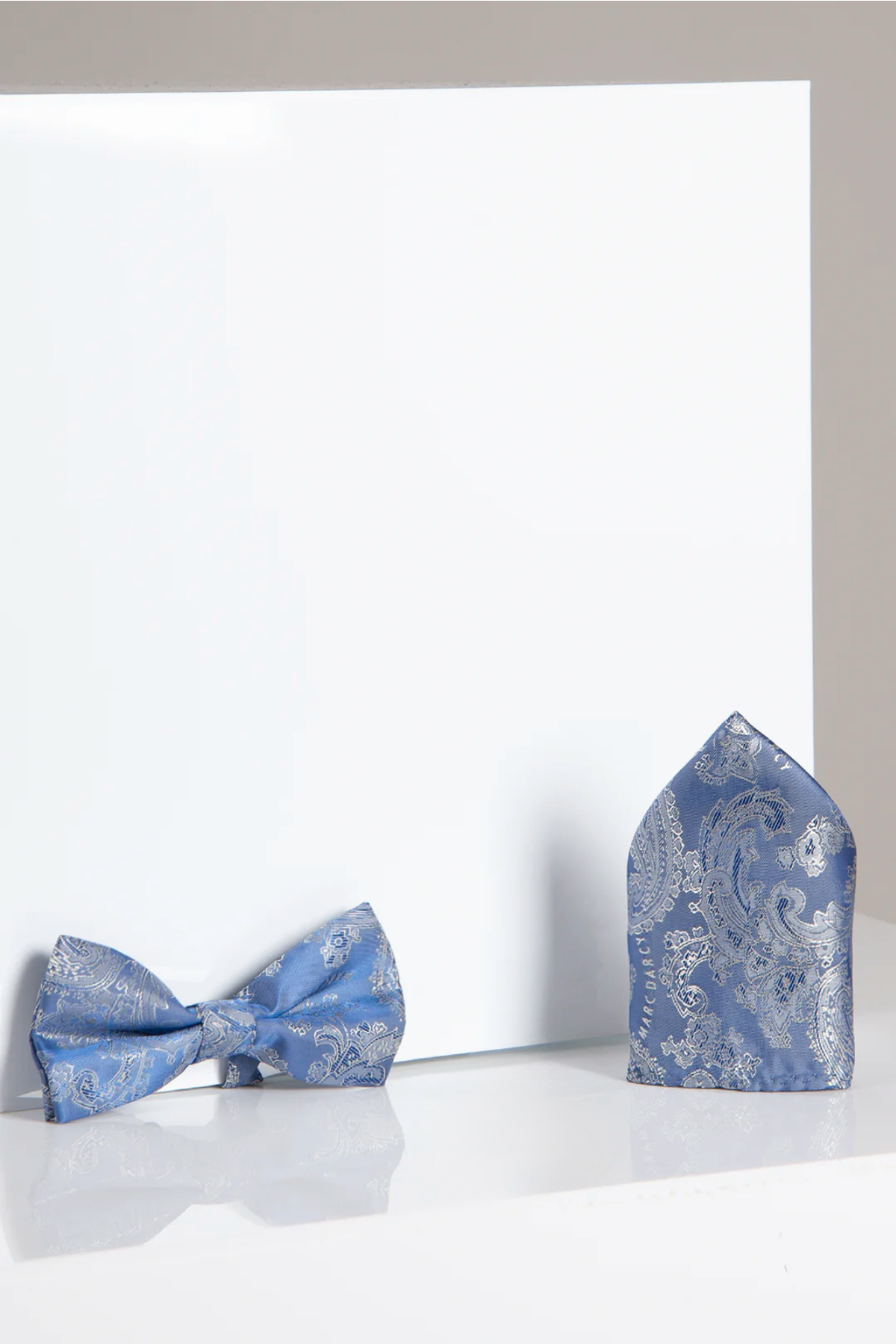 The MD PAISLEY - Sky Blue Paisley Bow Tie and Pocket Square Set by Accessory is shown on a white background, with the pocket square standing upright and the bow tie laid flat.