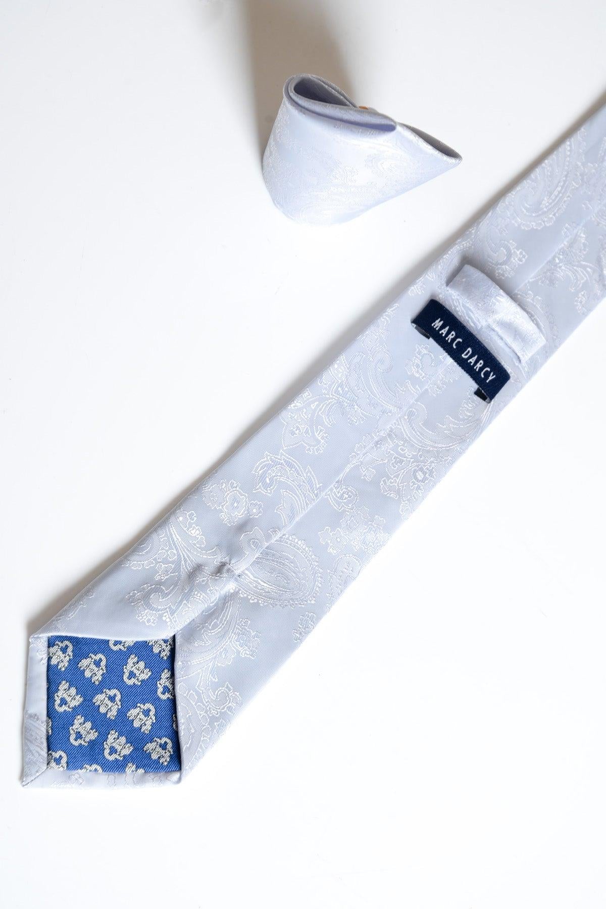The MD PAISLEY Silver Paisley Tie and Pocket Square Set by Accessory features a light grey paisley print, a blue floral pattern on the underside of the tie tip, and a MARC DARCY label. Both are shown against a white background.