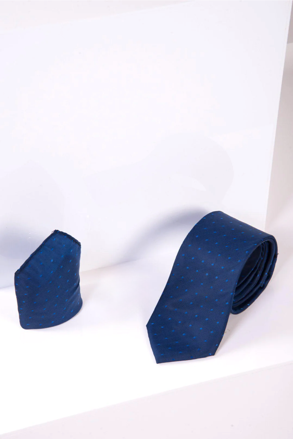 The TS POLKA DOT - Blue Polka Dot Tie and Pocket Square Set by Accessory is displayed on a white surface, featuring a navy blue tie with light blue dots—ideal for a refined formal look.
