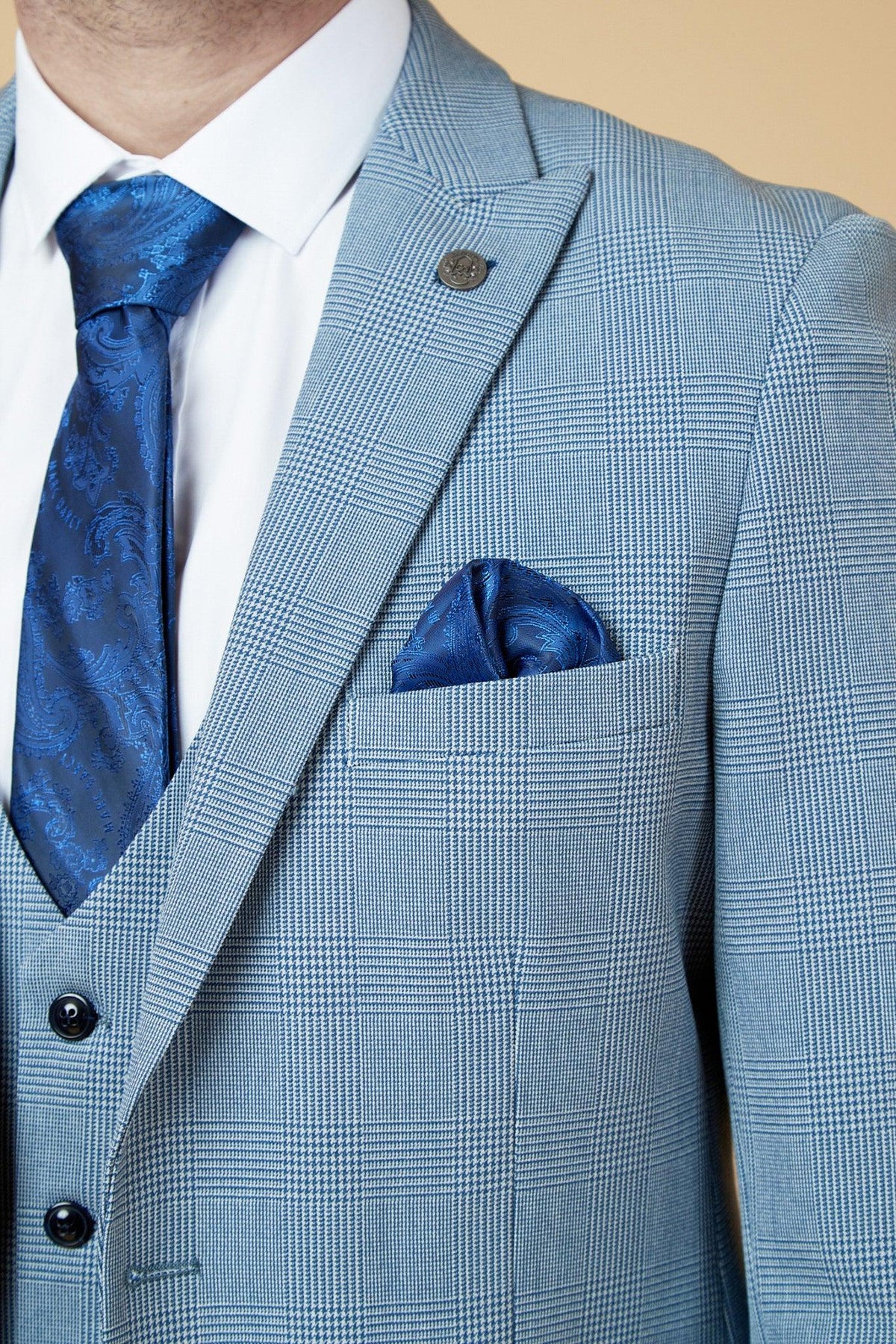 A man wears The WBA Collection - BROMLEY sky blue suit by Marc Darcy, as worn by Brandon Thomas-Asante, with a Prince of Wales check, paisley blue tie and pocket square, and a crisp white shirt.