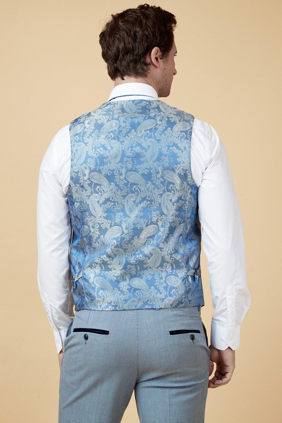 Back view of a man wearing the Marc Darcy WBA Collection - BROMLEY suit as worn by Brandon Thomas-Asante, featuring a sky blue paisley-detailed vest, white shirt, and light blue Prince of Wales check trousers.