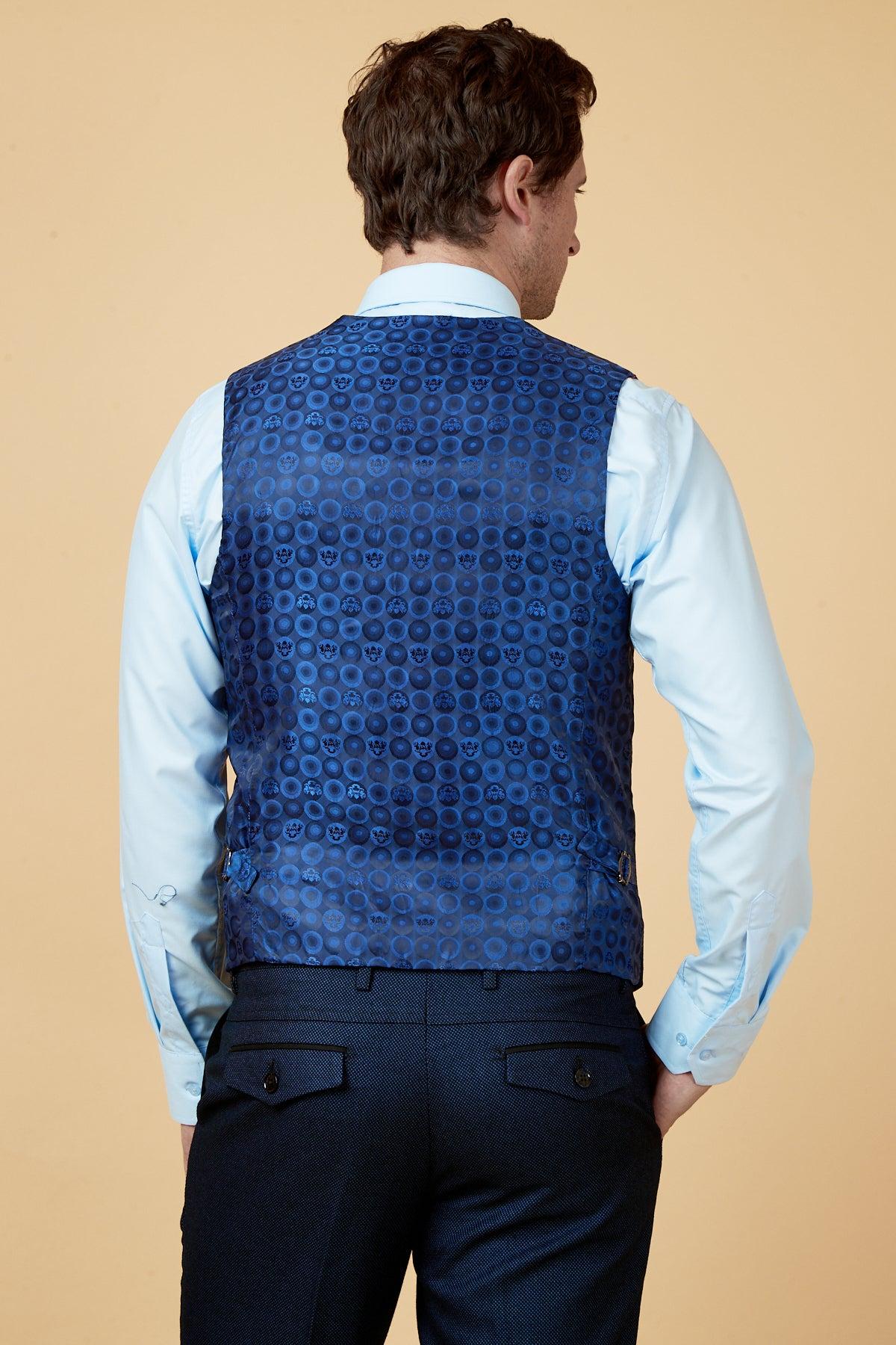 Back view of a man wearing a light blue dress shirt, navy pants, and the marcdarcy CALLUM Blue Waistcoat with a circular pattern—an ideal choice for elevating any sharp work wardrobe.