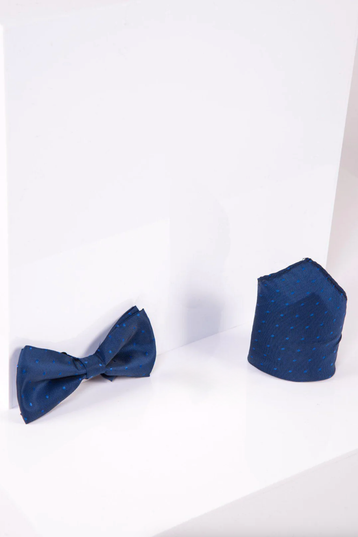 The Accessory BT POLKA DOT set, featuring a blue polka dot pre-tied bow tie and matching pocket square, is displayed on a white surface—ideal for evening events.