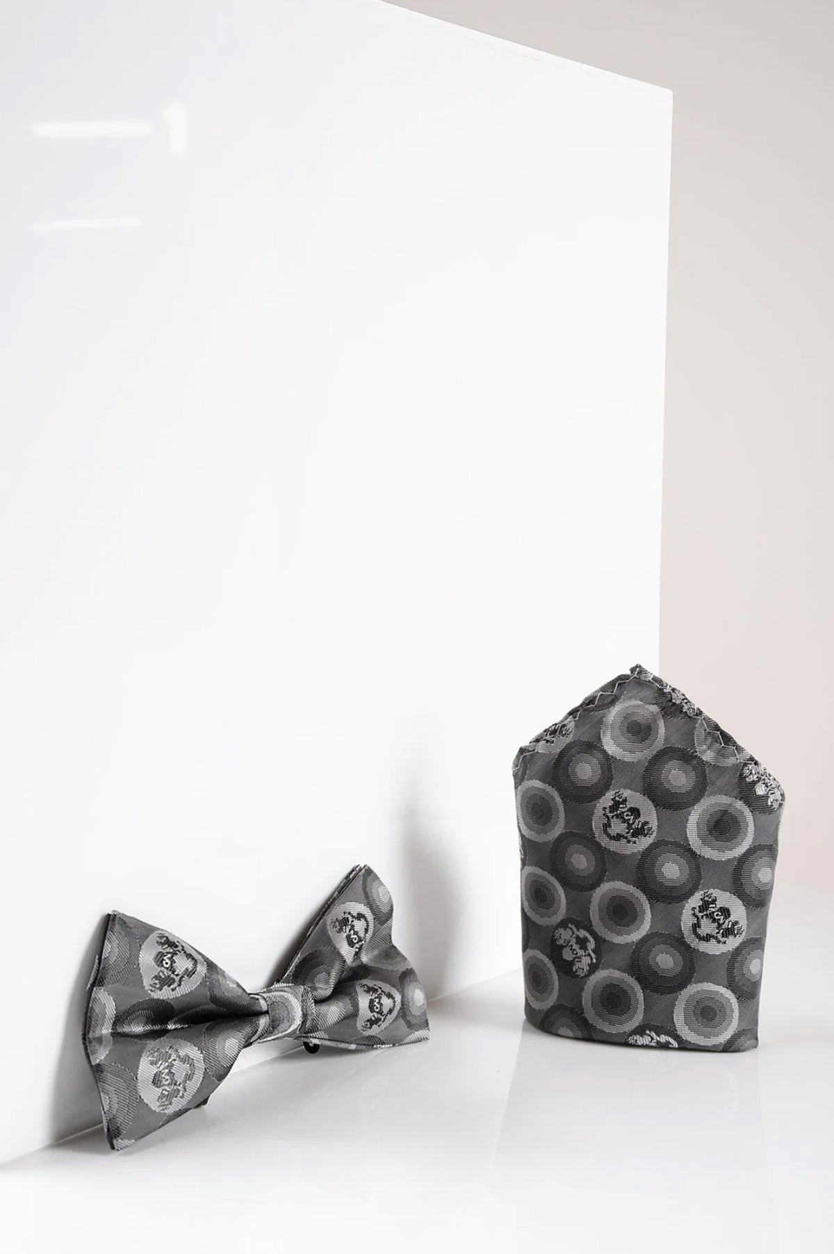 The BUBBLES - Grey Bubble Circle Print Bow Tie and Pocket Square Set by Marc Darcy sits elegantly on a white surface, making it perfect for formalwear.