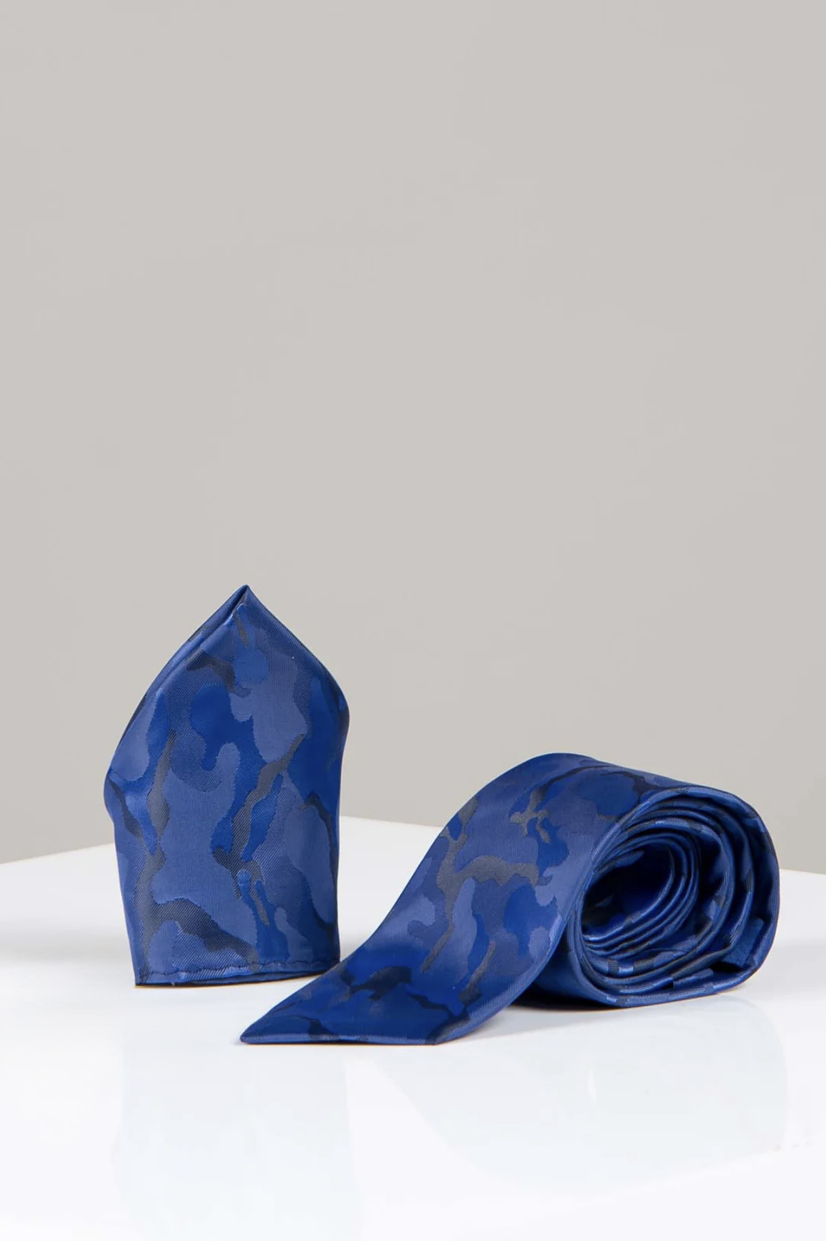 The TS ARMY - Navy Camouflage Tie and Pocket Square Set by Accessory features a striking blue camo tie and matching pocket square, displayed on white with a gray backdrop—ideal for upgrading your formalwear.