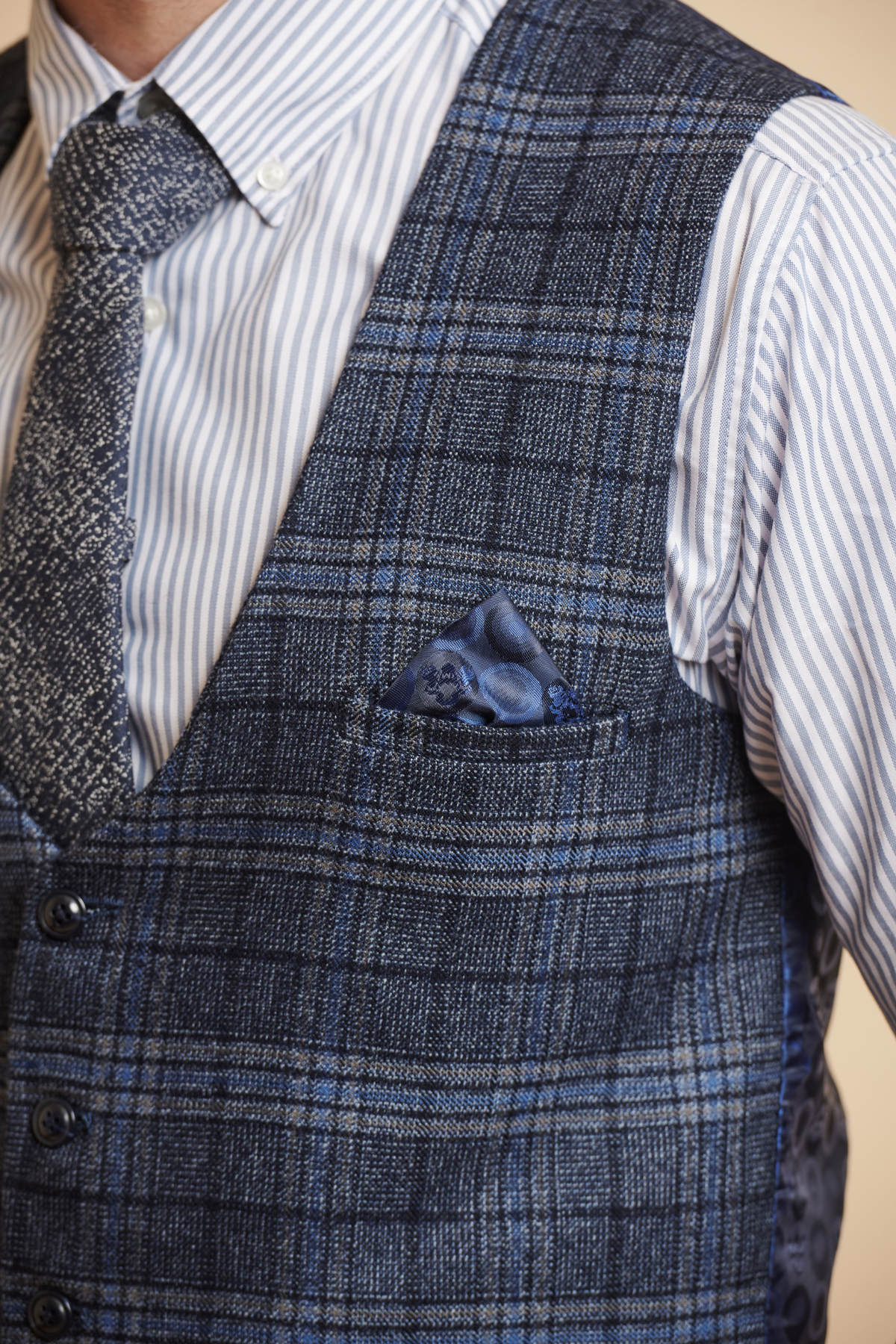 A man in formalwear wears a blue and white striped shirt, slim blue tie, and the Marc Darcy ANDY Blue Single Breasted Check Waistcoat with matching pocket square. The image is cropped to show only his upper torso.