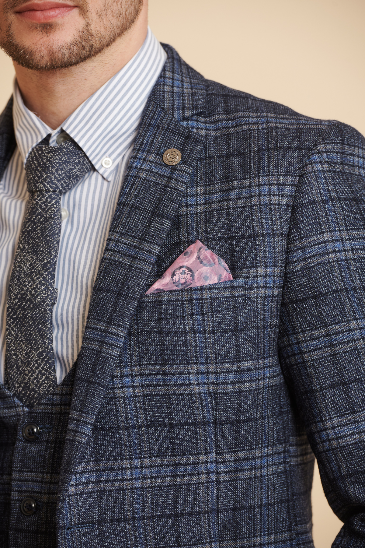 James Tarkowski models the ANDY Blue Check Suit from Marc Darcy’s Everton Collection, styled with a striped shirt, patterned tie, and pink paisley pocket square, shown from shoulders to mid-chest facing slightly left.