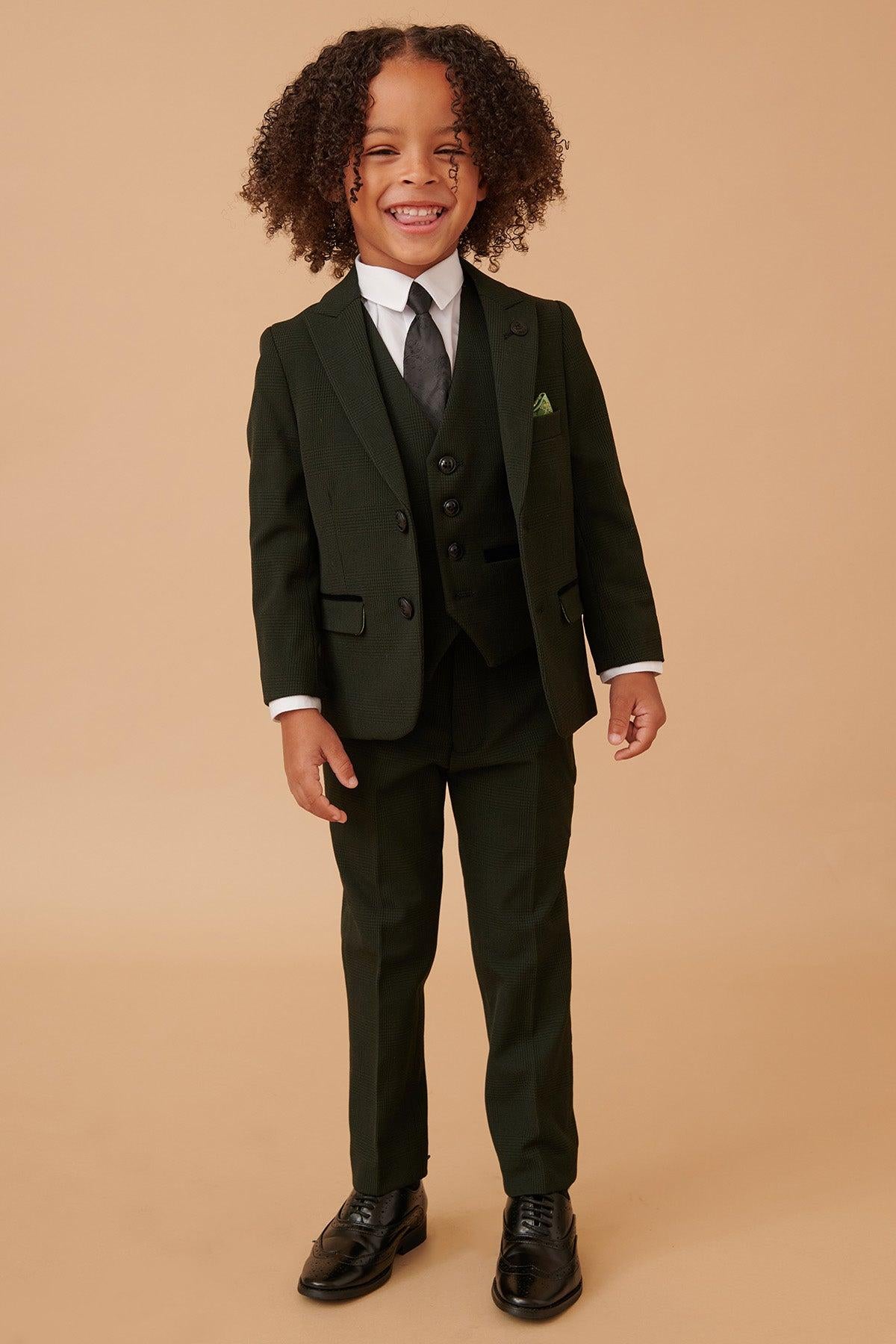 A young child with curly hair smiles against a beige background, wearing the Marc Darcy BROMLEY Children's Olive Green Check Print Three Piece Suit.