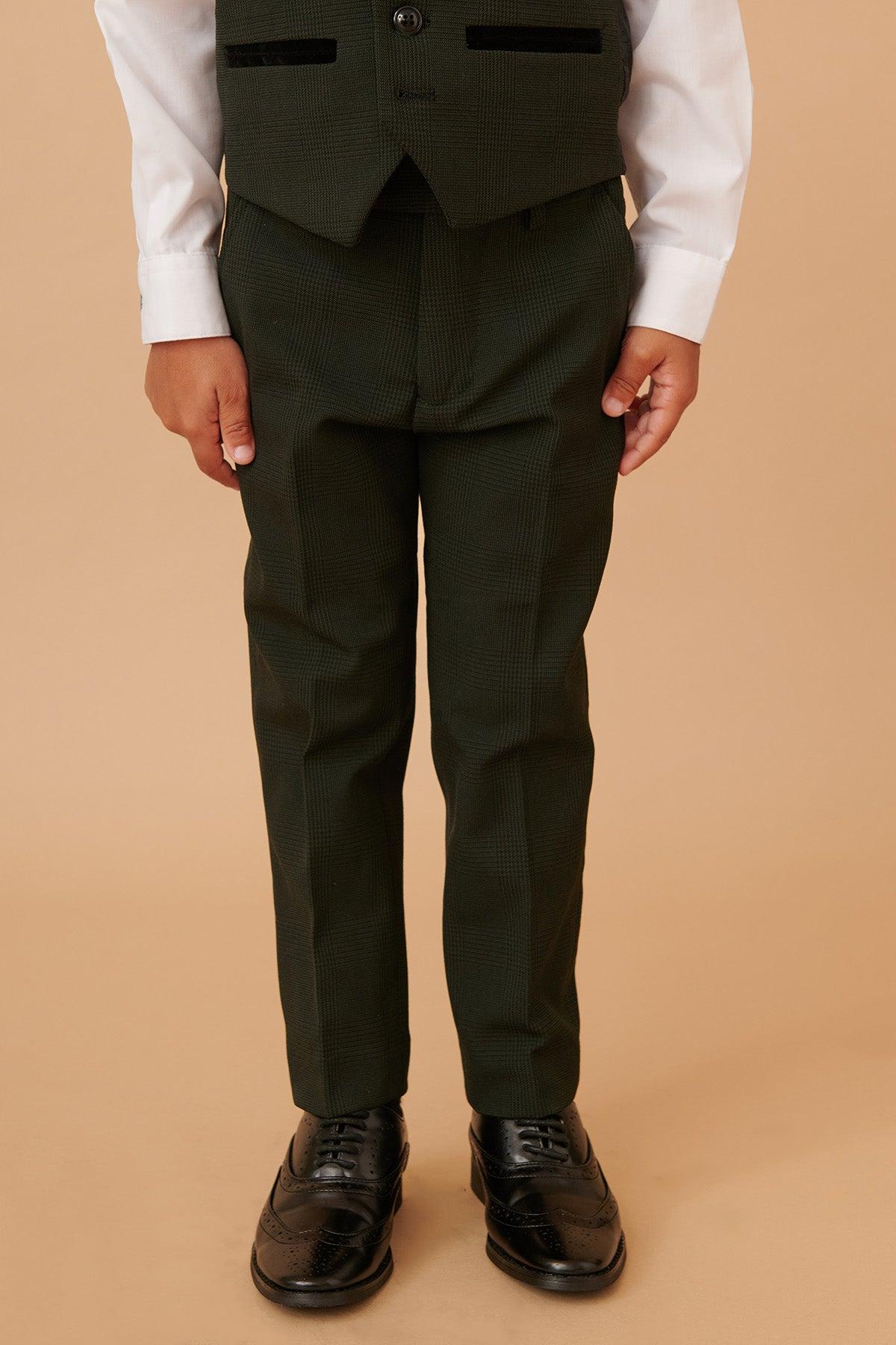 A young boy wears the Marc Darcy BROMLEY Childrens Olive Green Check Print Three Piece Suit, featuring dark green pants, a matching vest, and white shirt. His body from shoulders down is shown against a beige background.