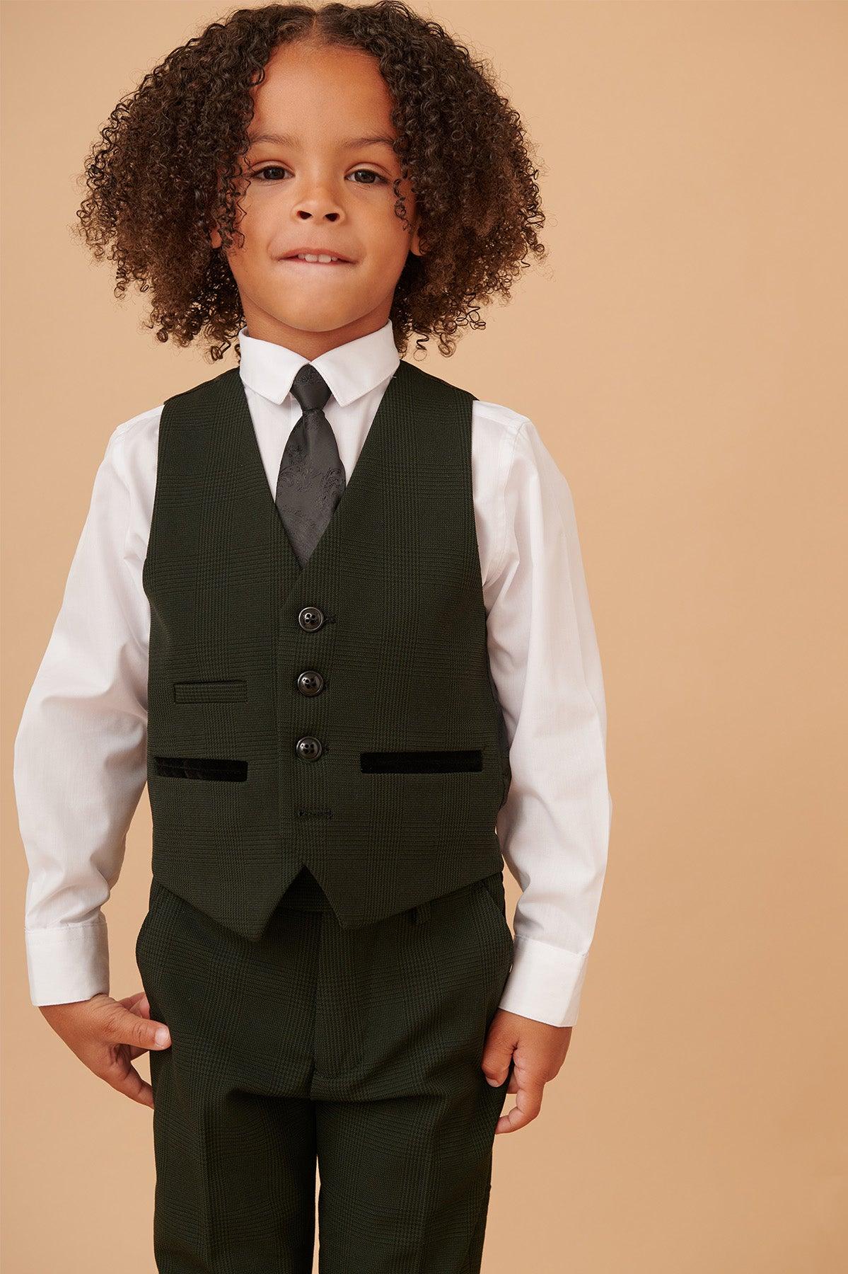 A young boy wears the BROMLEY Children's Olive Green Check Print Three Piece Suit by Marc Darcy, paired with a white dress shirt and patterned tie for a charming look.