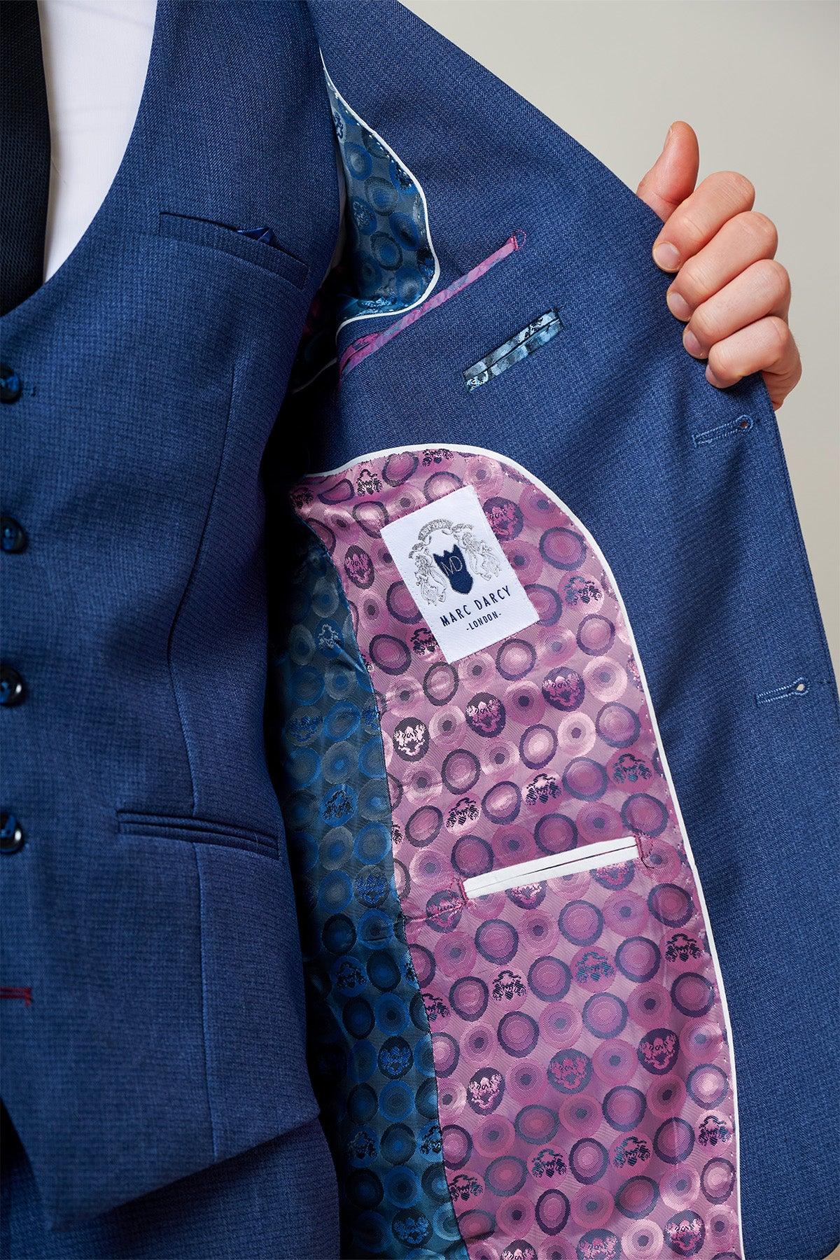 A person holds open the ASHLEY Navy Blue Two Piece Suit by Marc Darcy, revealing its vibrant interior lining with a purple and pink geometric skull pattern—a versatile piece with standout details.