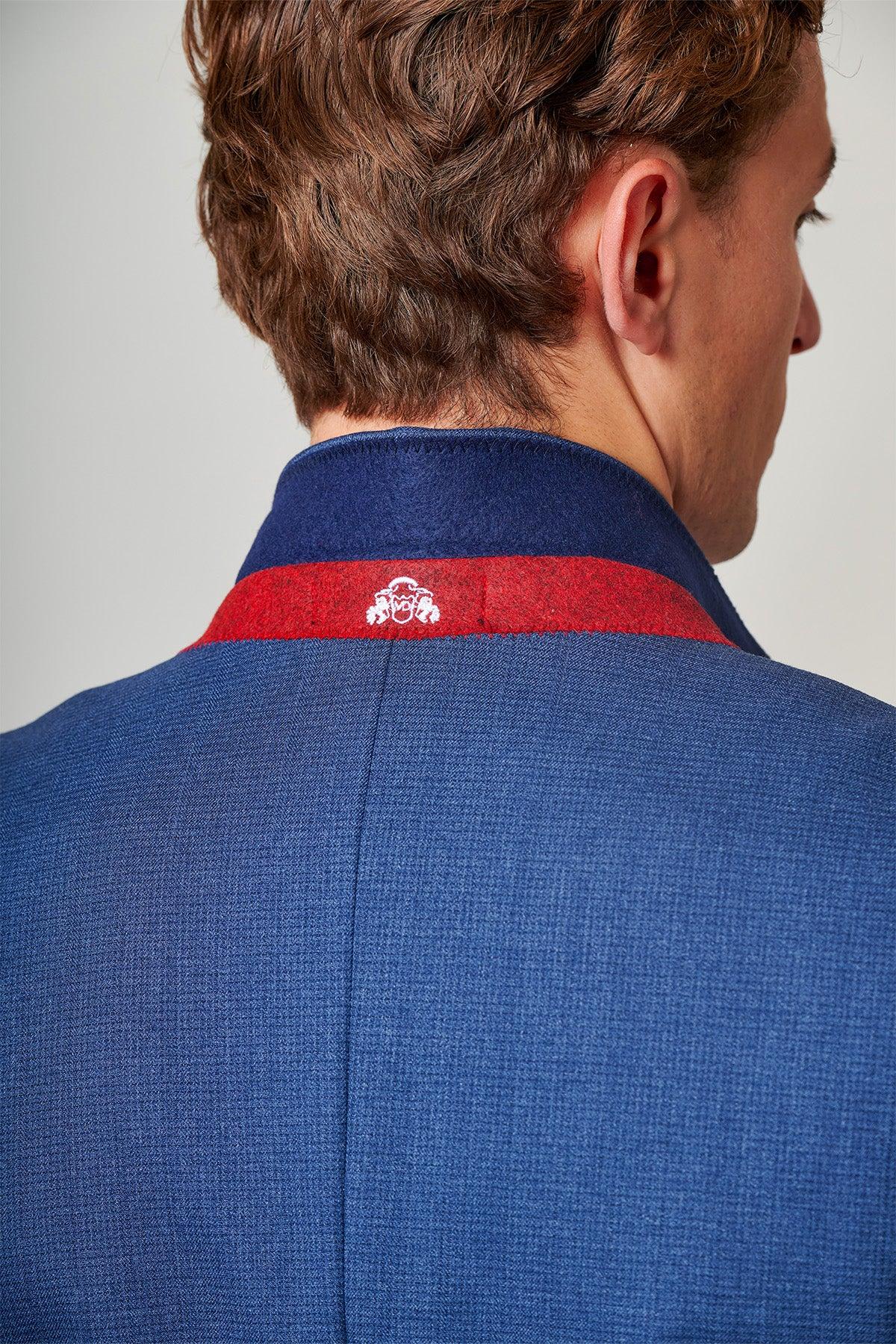 A man shown from behind wears the Marc Darcy ASHLEY Navy Blue Two Piece Suit, featuring a slim fit, red stripe detail, and a small white embroidered logo on the collar—a versatile addition to any wardrobe.