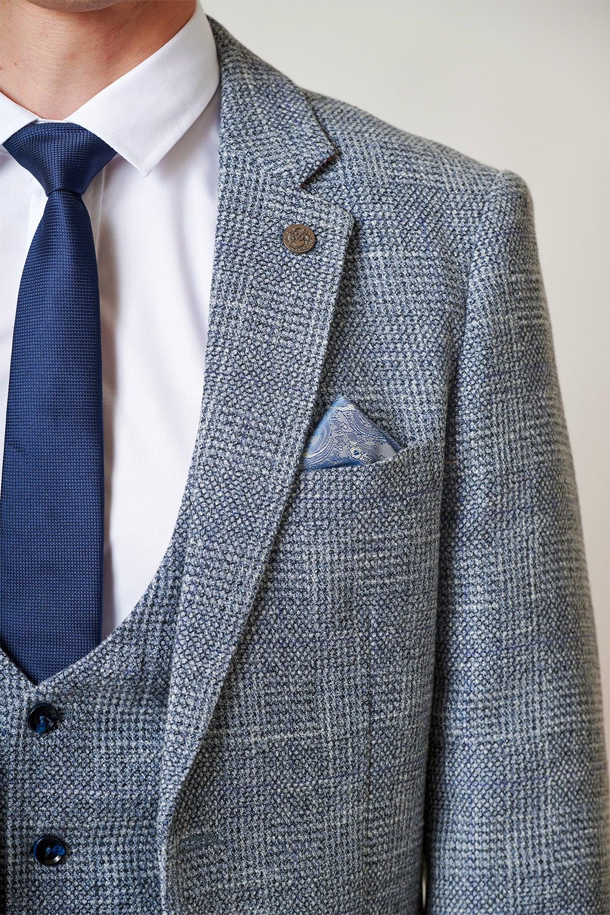 A close-up of a person wearing the marcdarcy KRIS - Sky Blue Tweed Two Piece Suit with a white shirt, blue tie, and patterned pocket square. The head is partially out of the frame.