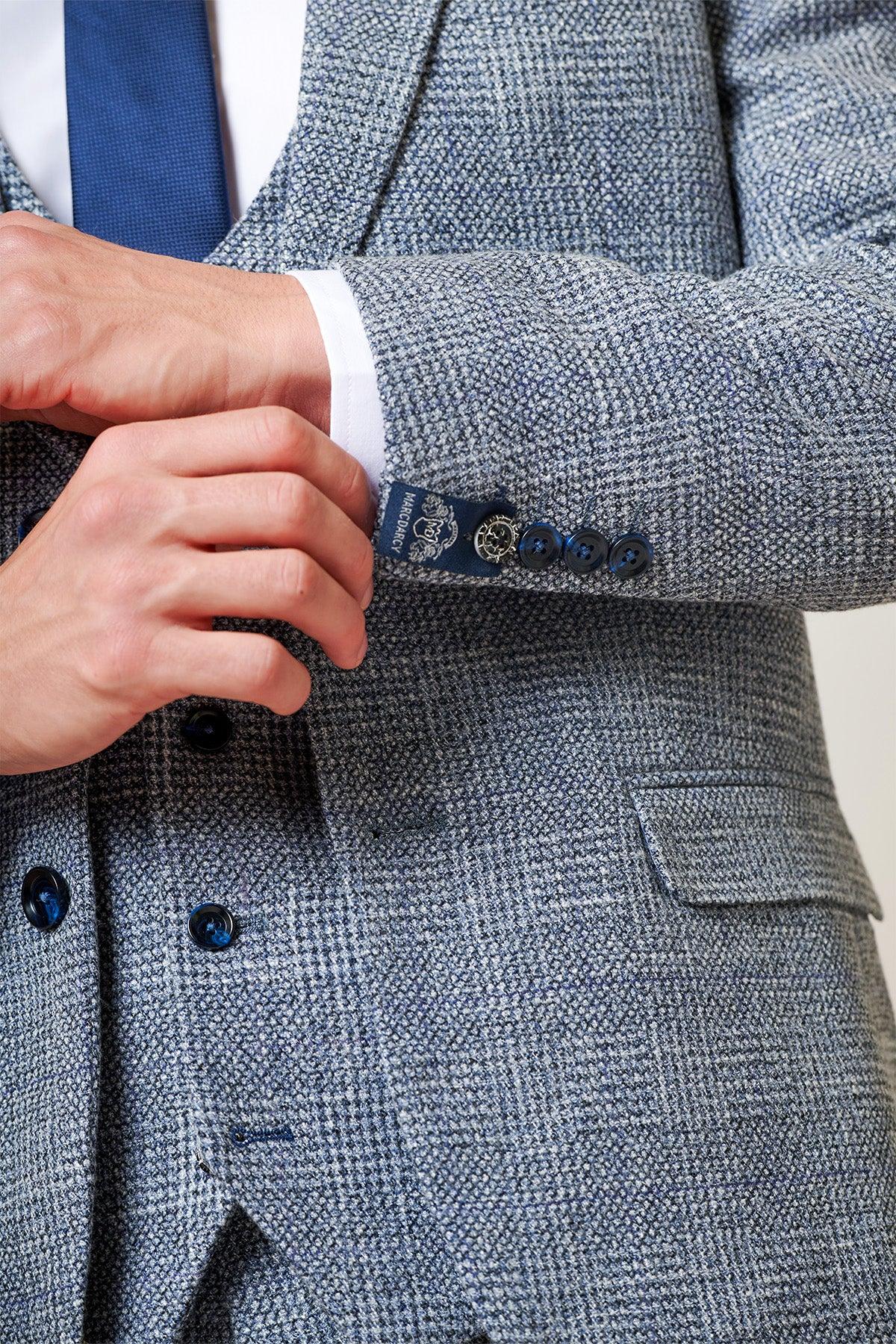 Close-up of Tim Iroegbunam in The Everton Collection KRIS Sky Blue Tweed Suit by marcdarcy. Features include a double-breasted waistcoat, navy buttons, and the signature marcdarcy label for a refined slim fit men’s look.