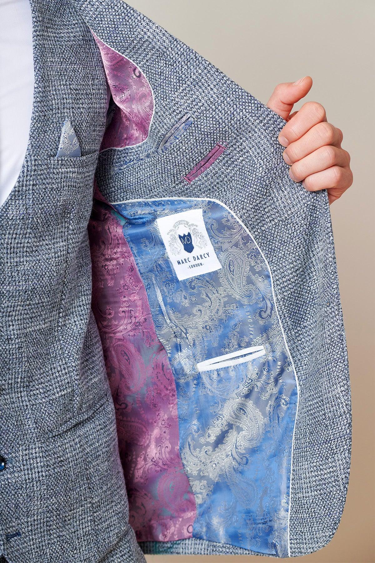 Close-up of The Everton Collection | Tim Iroegbunam In KRIS Sky Blue Tweed Suit by marcdarcy, showcasing the slim fit men's blazer and its striking blue and pink paisley patterned lining as a hand pulls open the lapel.