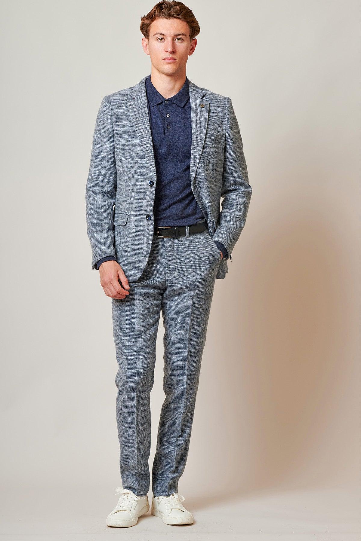 A man stands facing forward, wearing the marcdarcy Everton Collection | Tim Iroegbunam in KRIS Sky Blue Tweed Suit against a plain light background. His hands are at his sides.