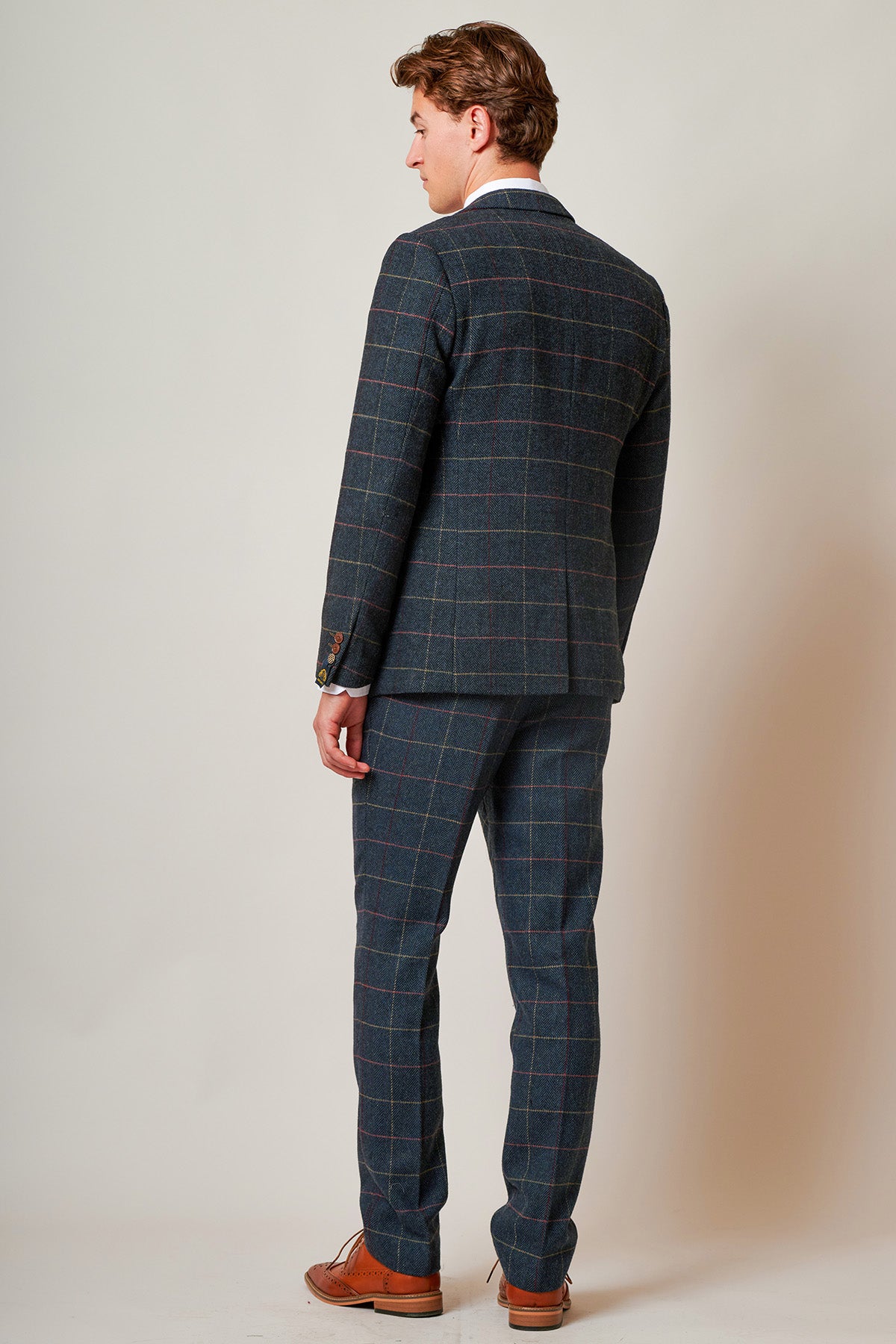 A man faces away, wearing the marcdarcy ETON Navy Blue Tweed Check Blazer and brown dress shoes, embodying smart casual style against a plain light background.