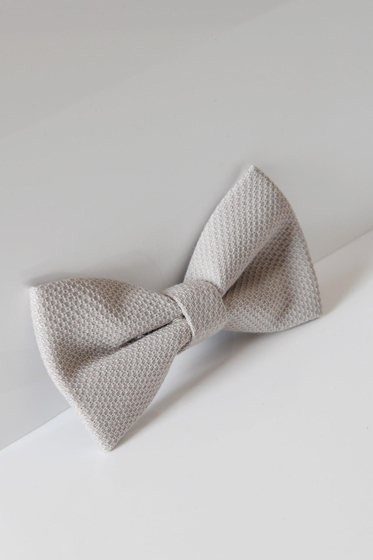 The HM5 - Stone Bow Tie by Accessory, featuring a grey textured design, rests elegantly on a white surface—an ideal choice for formalwear.