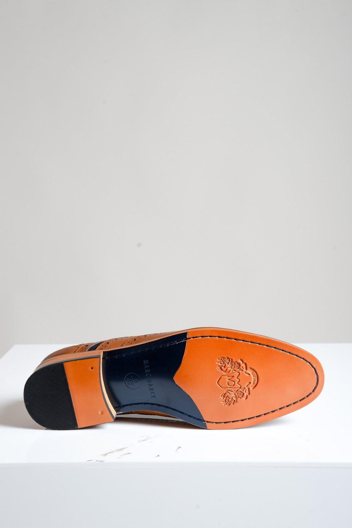 A single Marc Darcy MURRAY Contrast Tan Leather Suede Brogue Shoe is displayed upside down, revealing its brown leather sole with black heel and midfoot, plus an embossed crest and logo. The shoe is set against a light plain background.